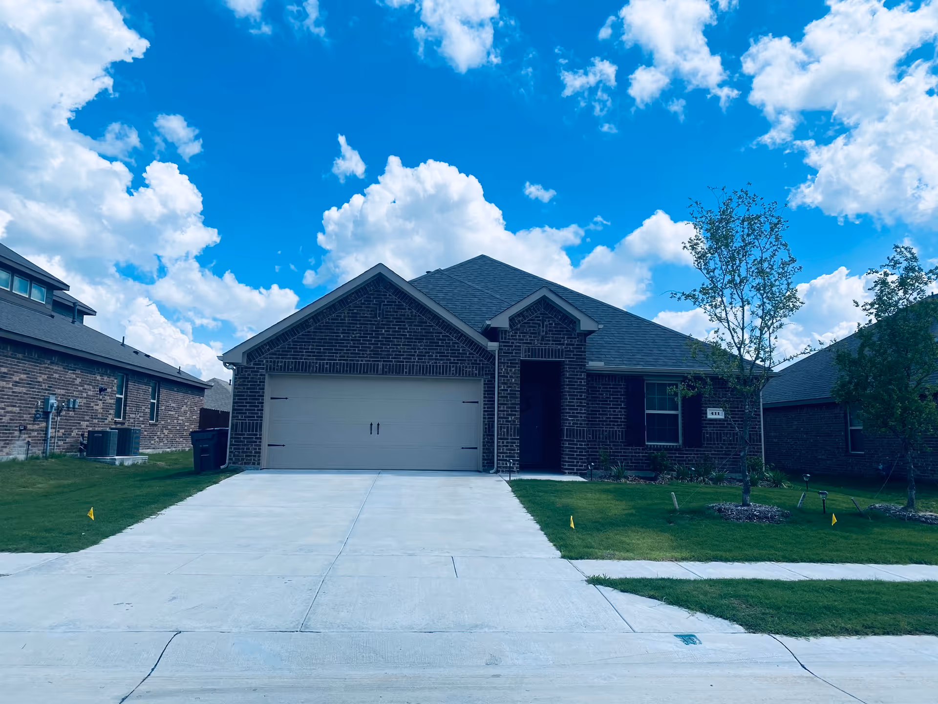 Front view of a brick residential home with a two-car garage and well-kept lawn.
