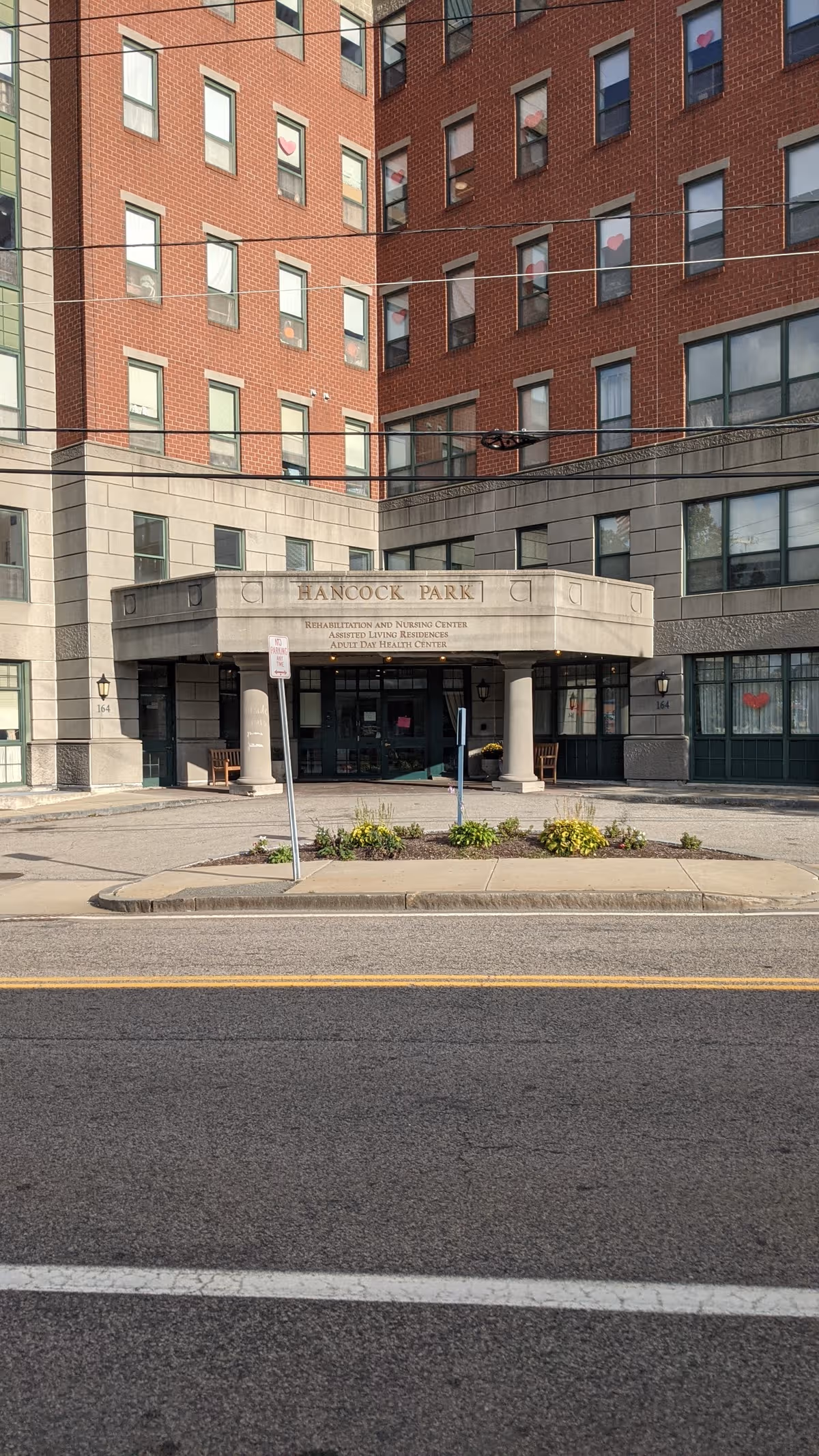 Front entrance of Hancock Park Assisted Living building with brick facade and canopy.