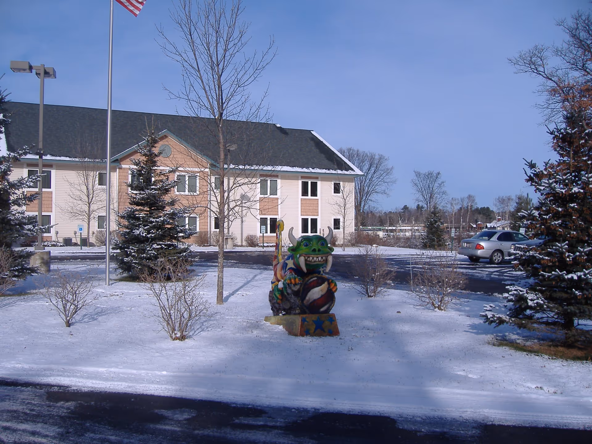 Snowy exterior of Grace Lodge Assisted Living with a colorful dragon statue near the entrance.