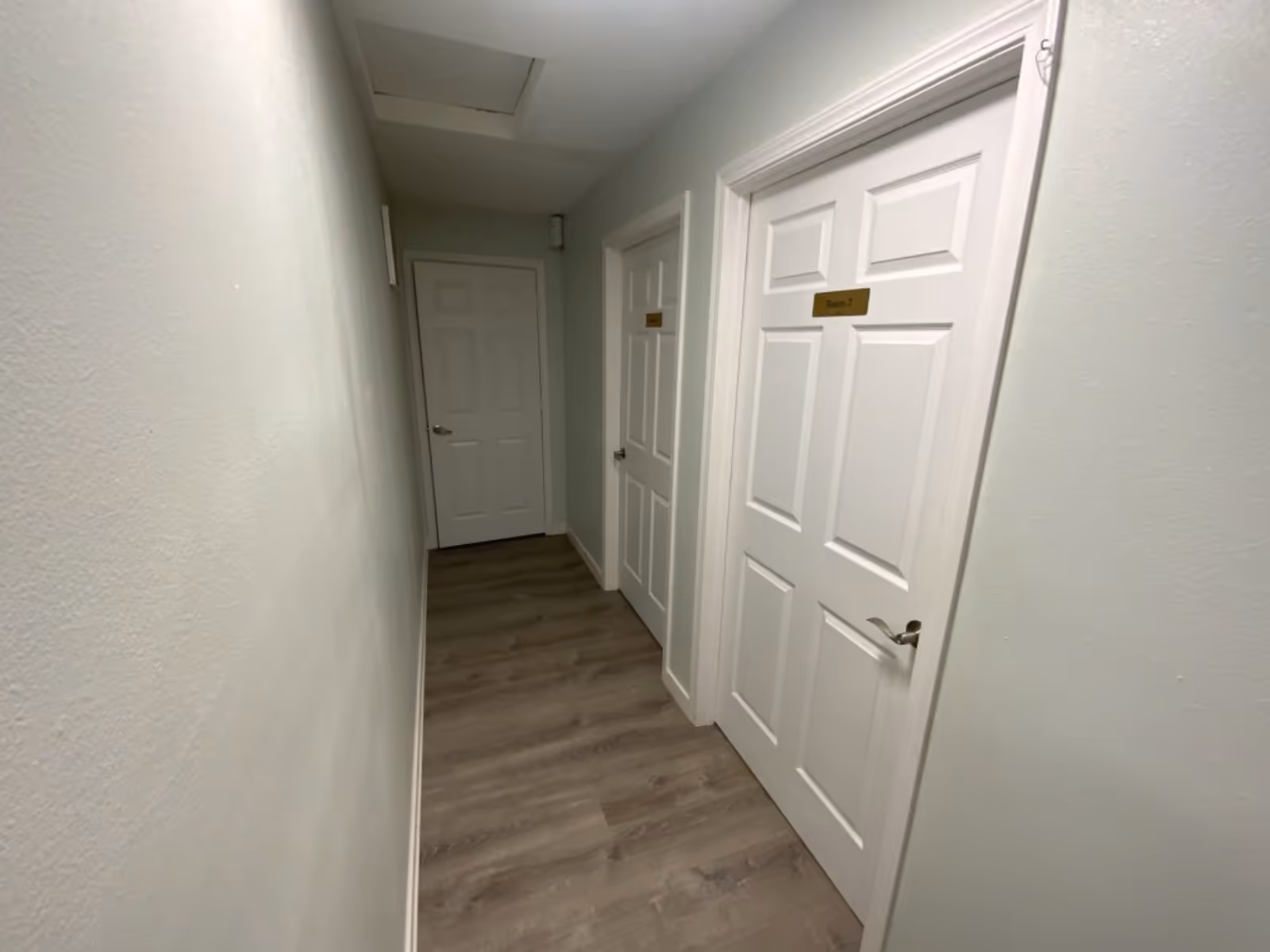 Interior hallway with white paneled doors and pale walls in a senior living facility.
