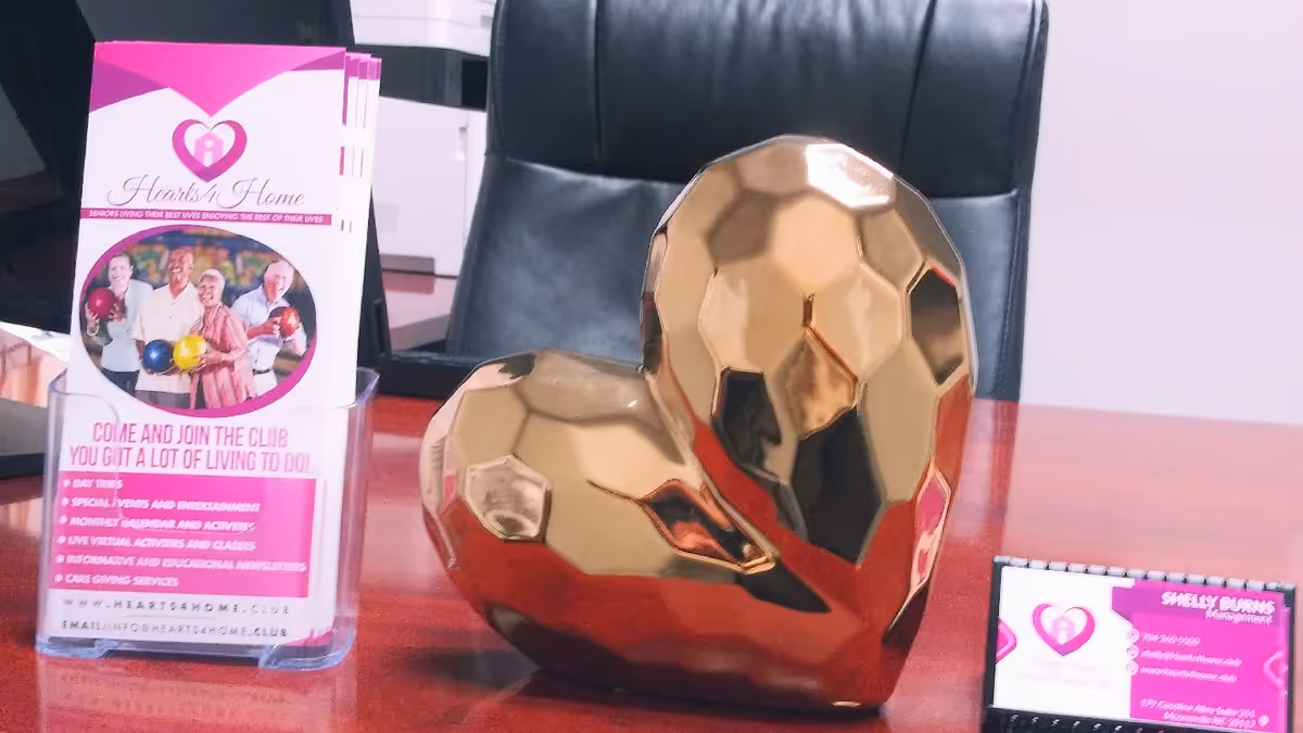 Gold geometric heart sculpture sits on a desk beside Hearts4home brochure in an office.