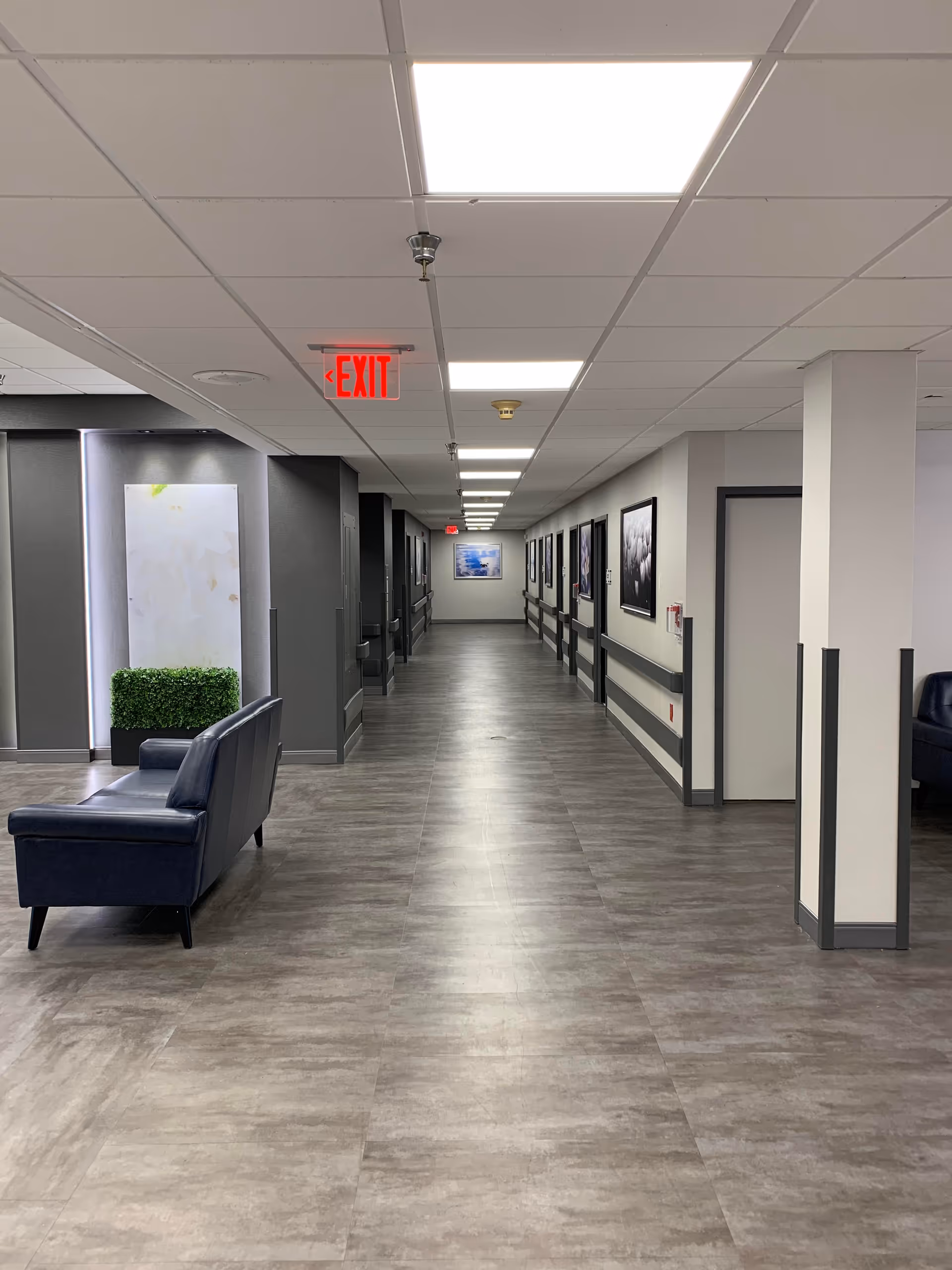 Bright corridor in a senior living facility with chairs and wall art.