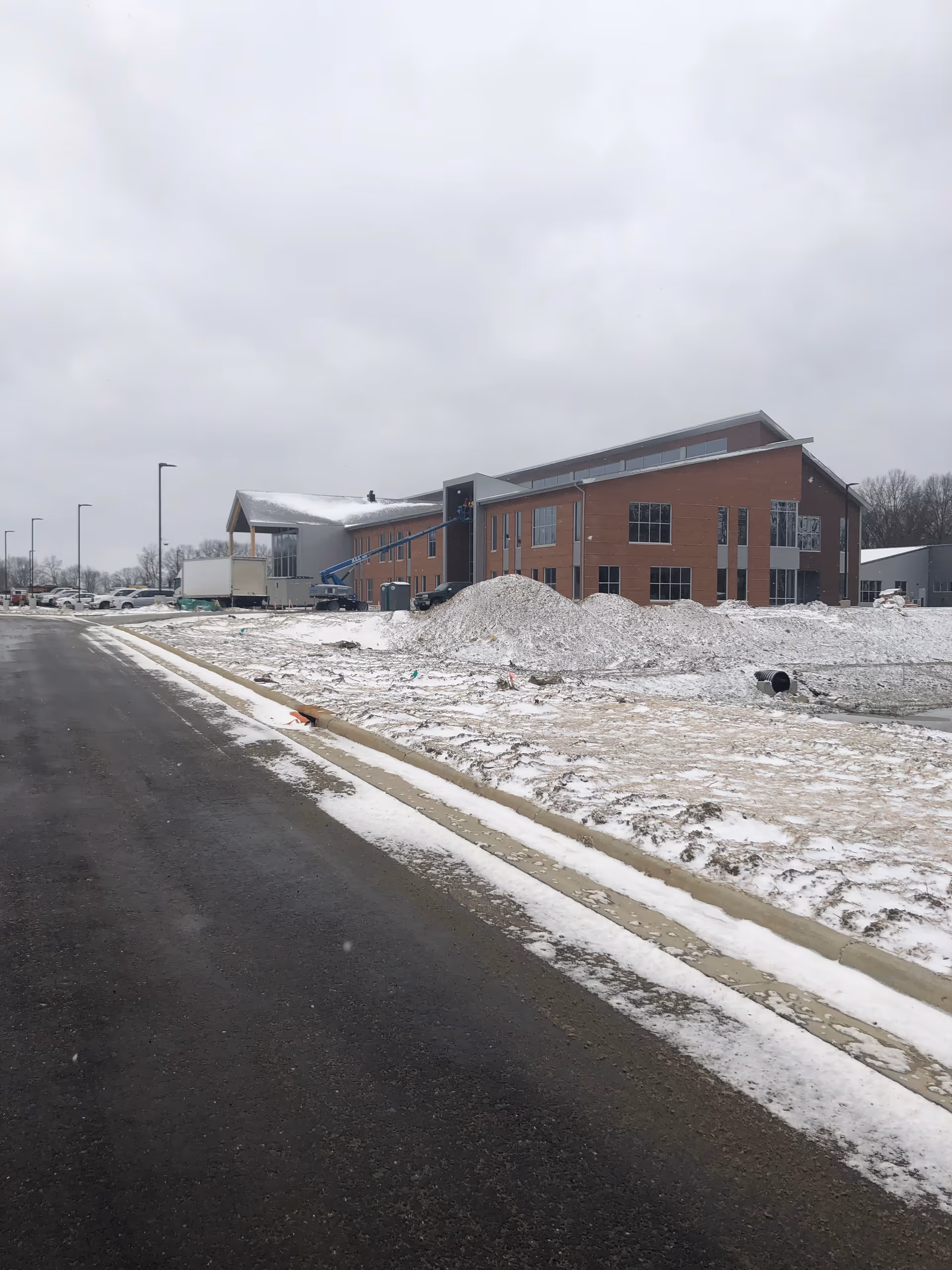 Brick building under construction beside a snowy street and curb