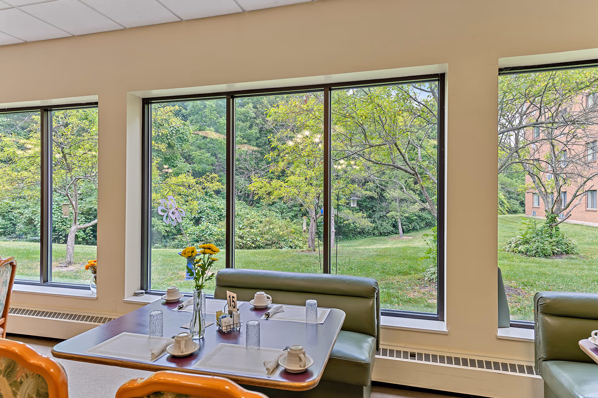 Sunlit dining area with tables set for meals and large windows.