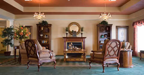 A formal Bailey Woods living room with upholstered chairs around a central fireplace.