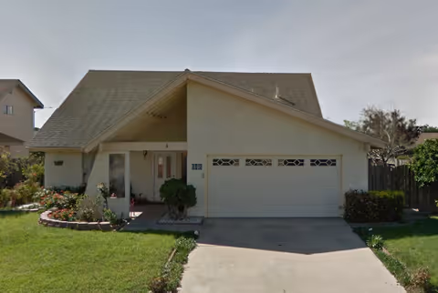 Single-story suburban house with a two-car garage, front lawn, and small porch.