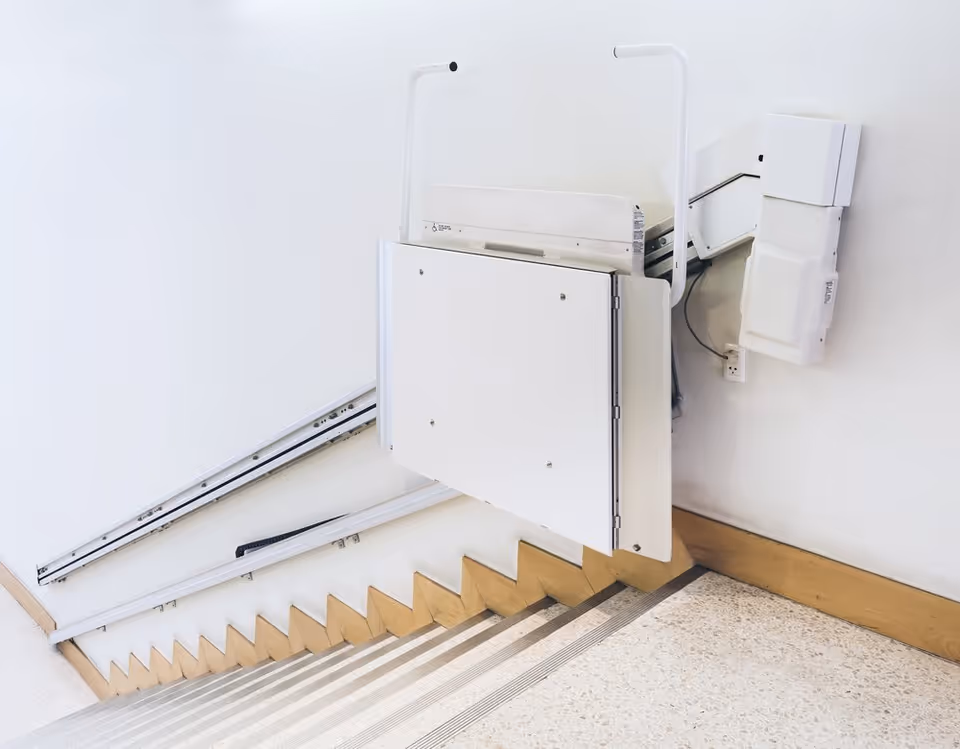A white indoor stairlift mounted along a stairway in a facility.