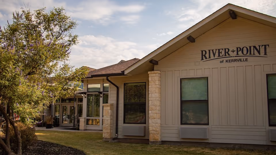 Exterior view of the River Point of Kerrville building with its name on the facade and a small grassy front area.