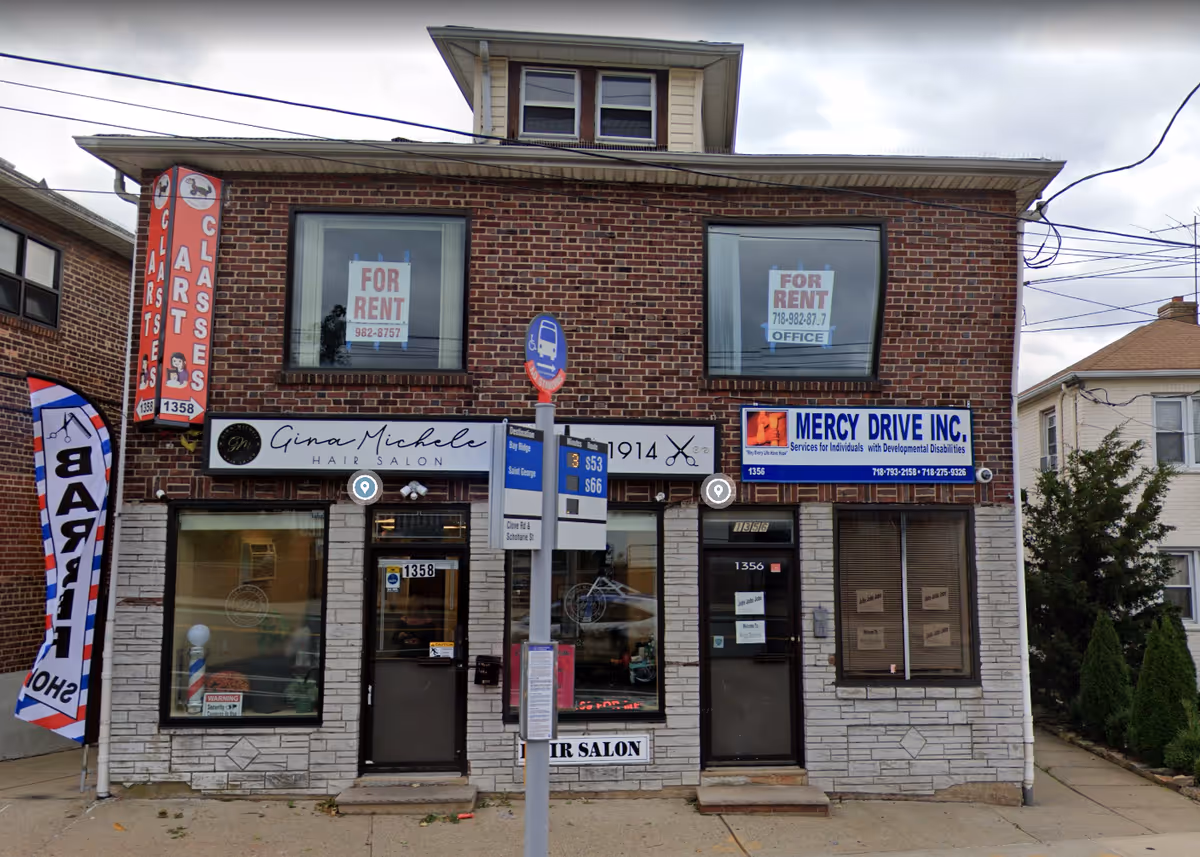Brick building with multiple storefronts, signs, and large display windows.