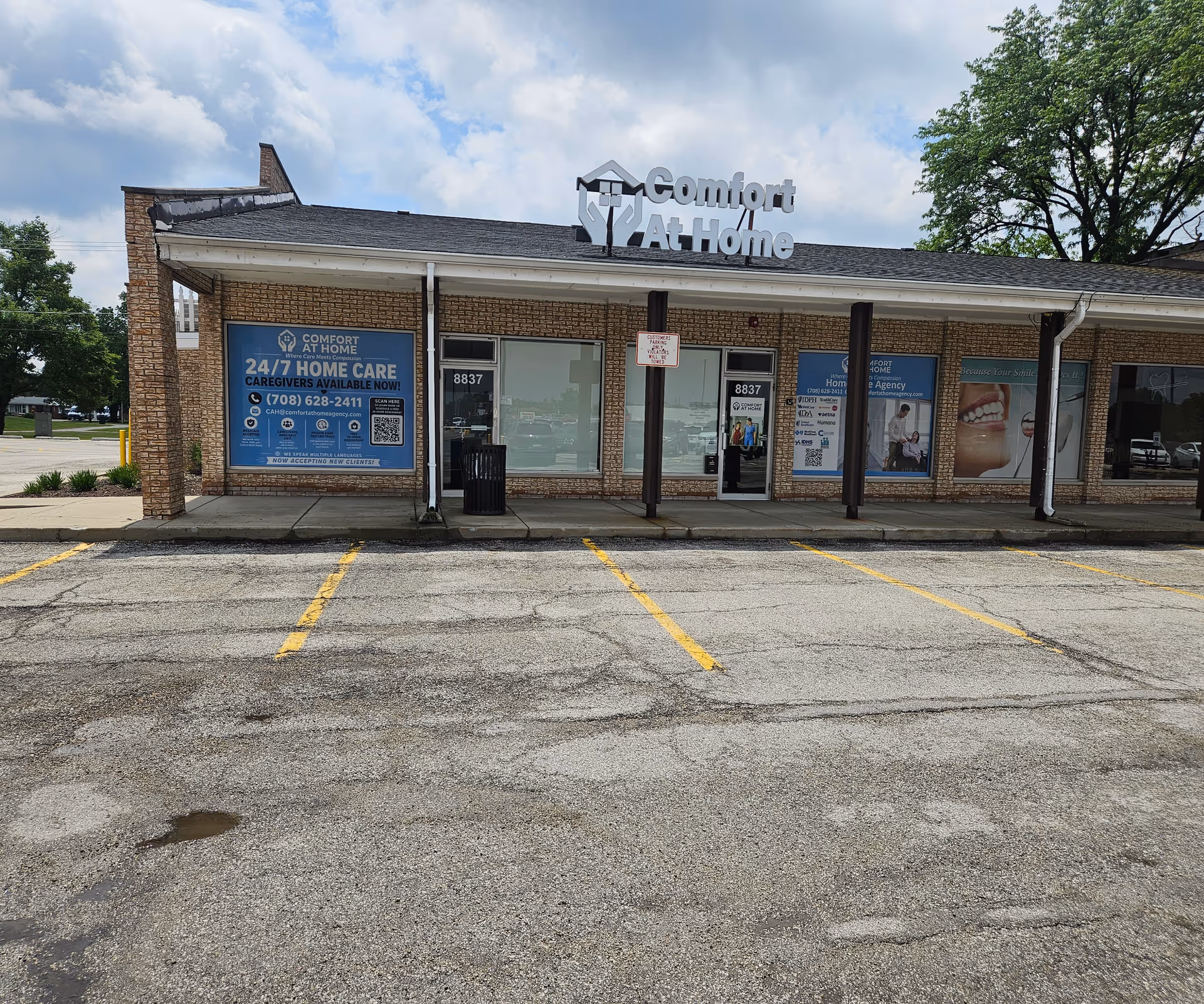 Front view of Comfort At Home LLC facility storefront with signage and posters.