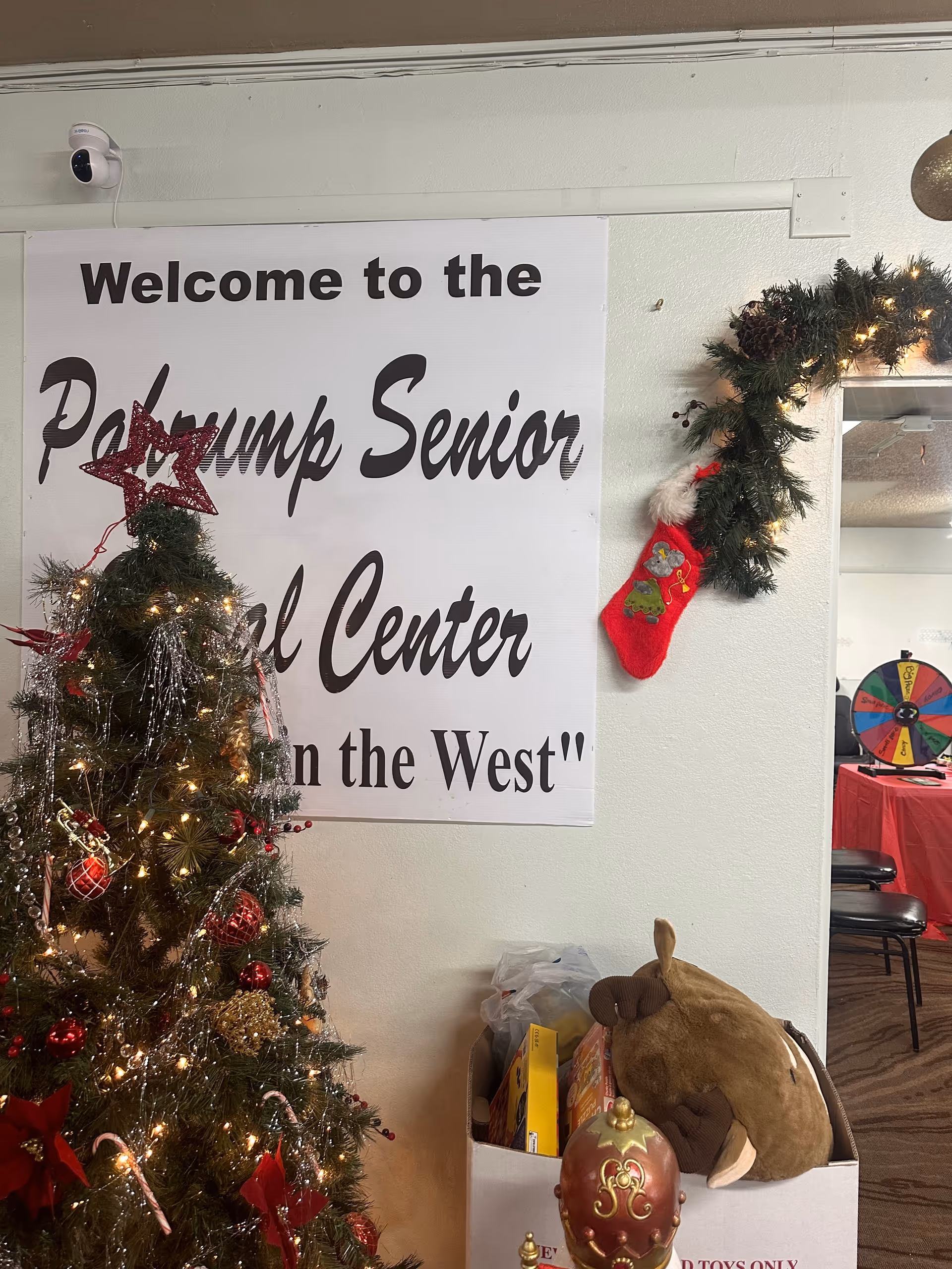 Interior lobby with a large welcome banner, Christmas tree, garland, and holiday decorations.
