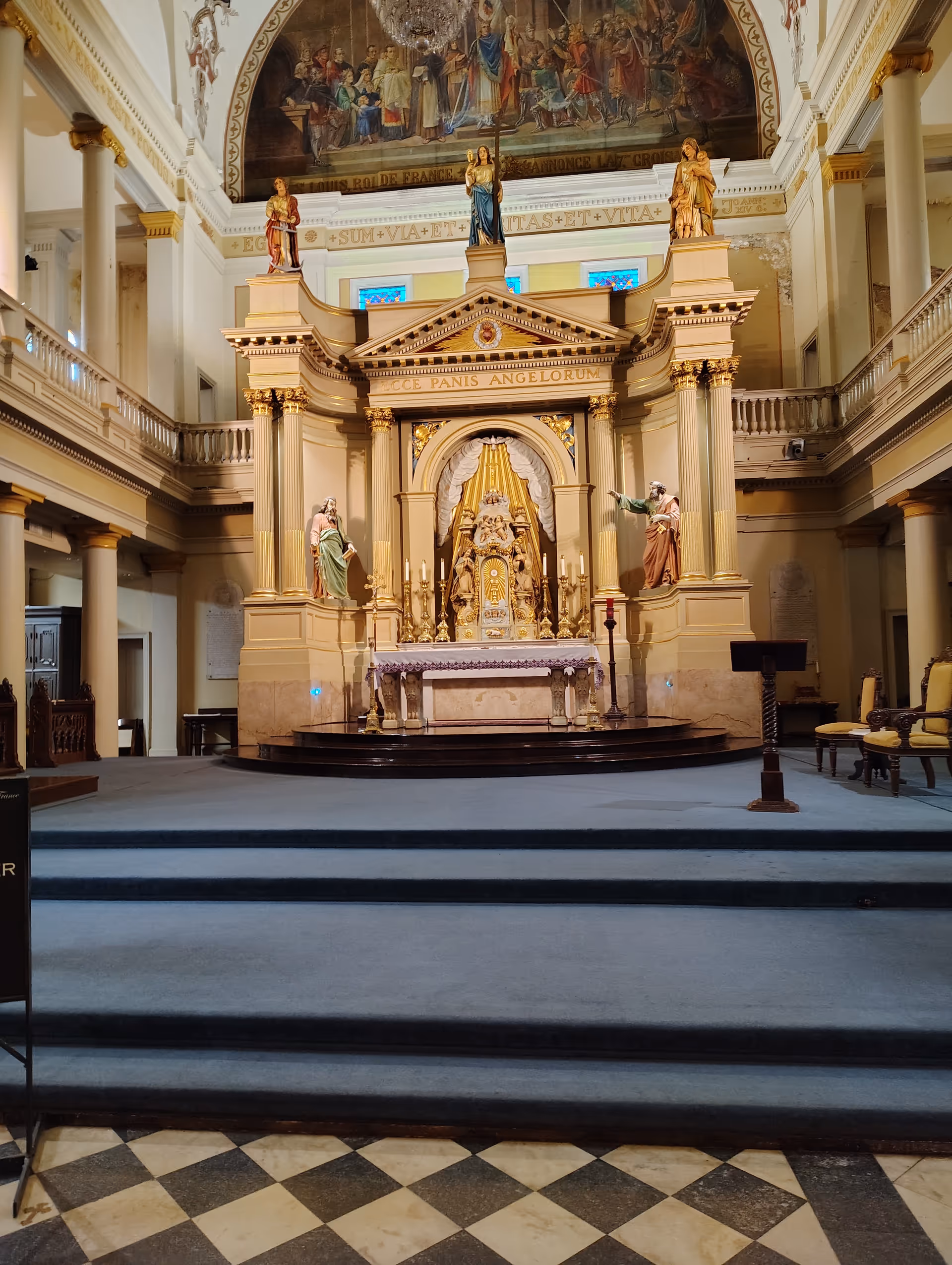 Ornate church altar inside a grand sanctuary with gold statues and arches.