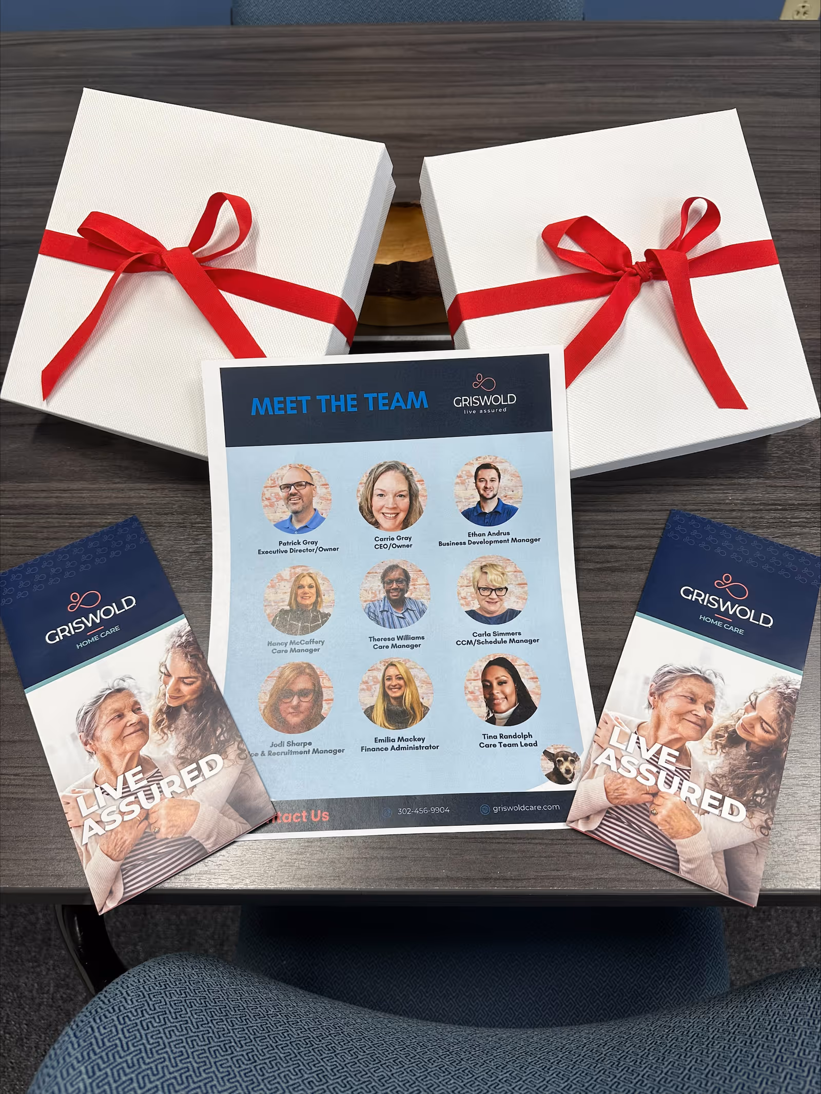 Promo materials and two white gift boxes with red ribbons on desk at Griswold.