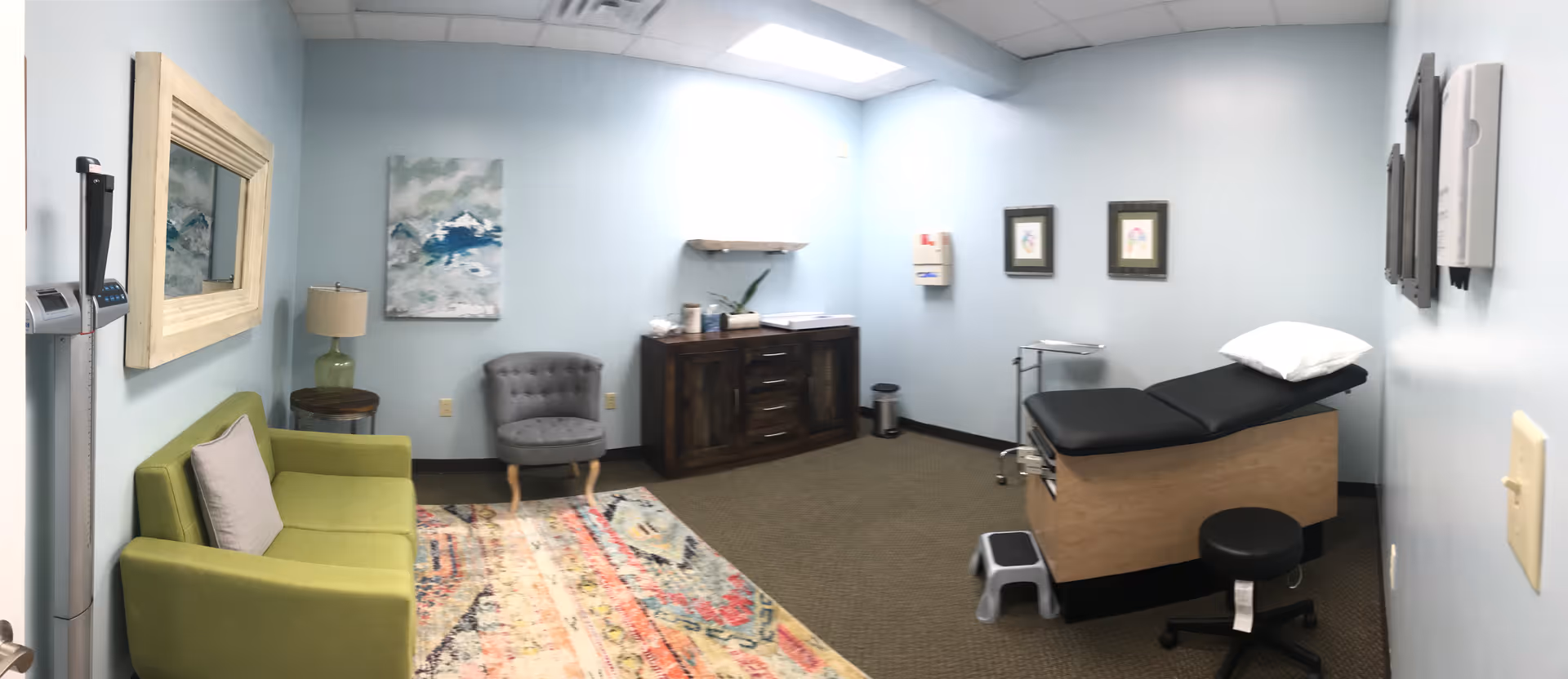 Interior of a senior living facility exam room with a treatment bed and chairs.