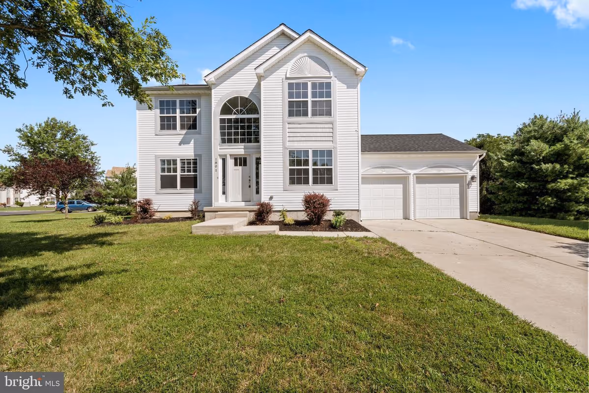 White two-story house with a two-car garage and manicured lawn.