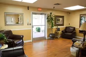 A comfortable living room lounge with leather chairs, plants, and a doorway to outdoors.