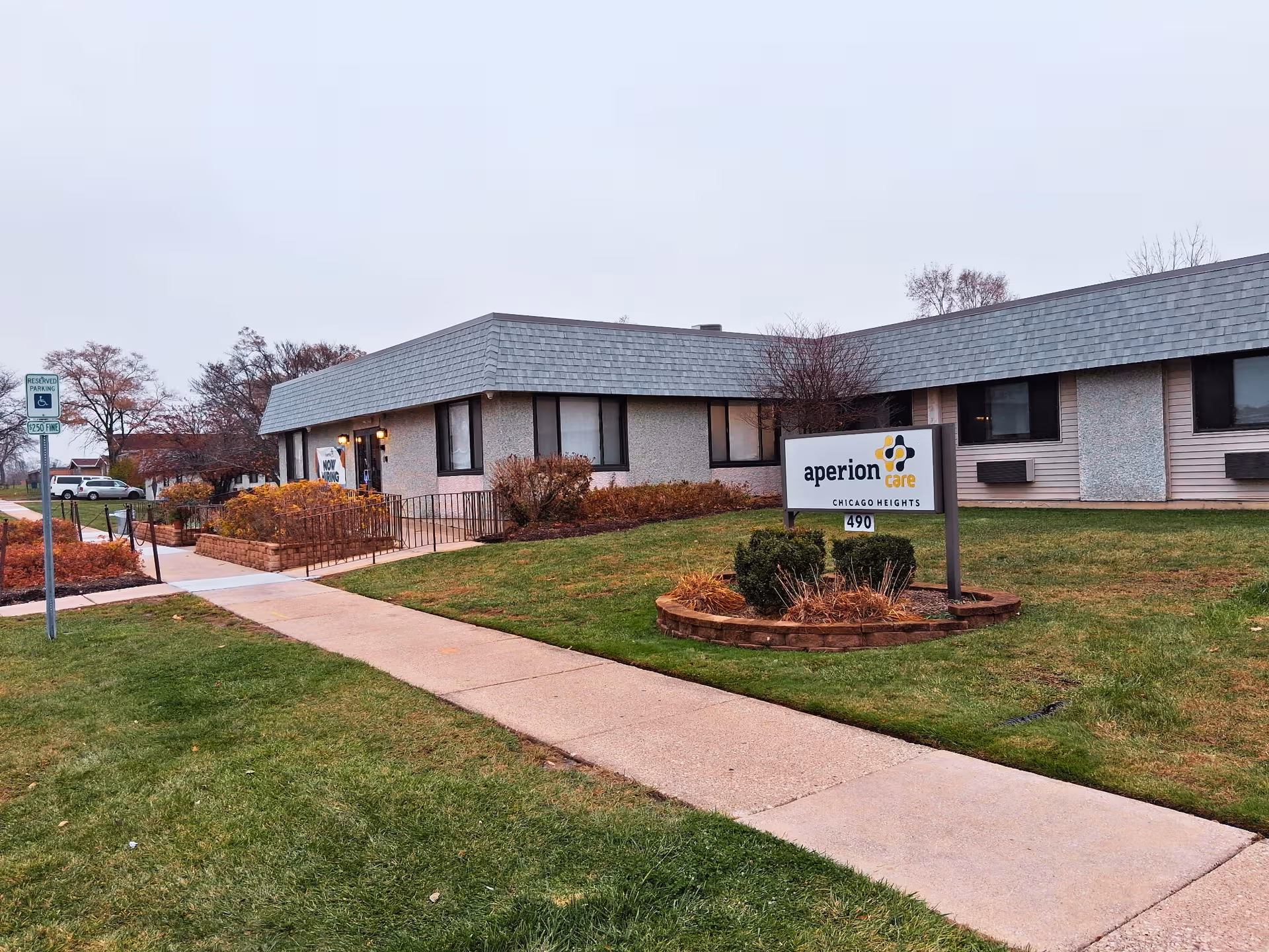 Single-story Aperion Care building with sign, walkway, and a well-kept lawn.