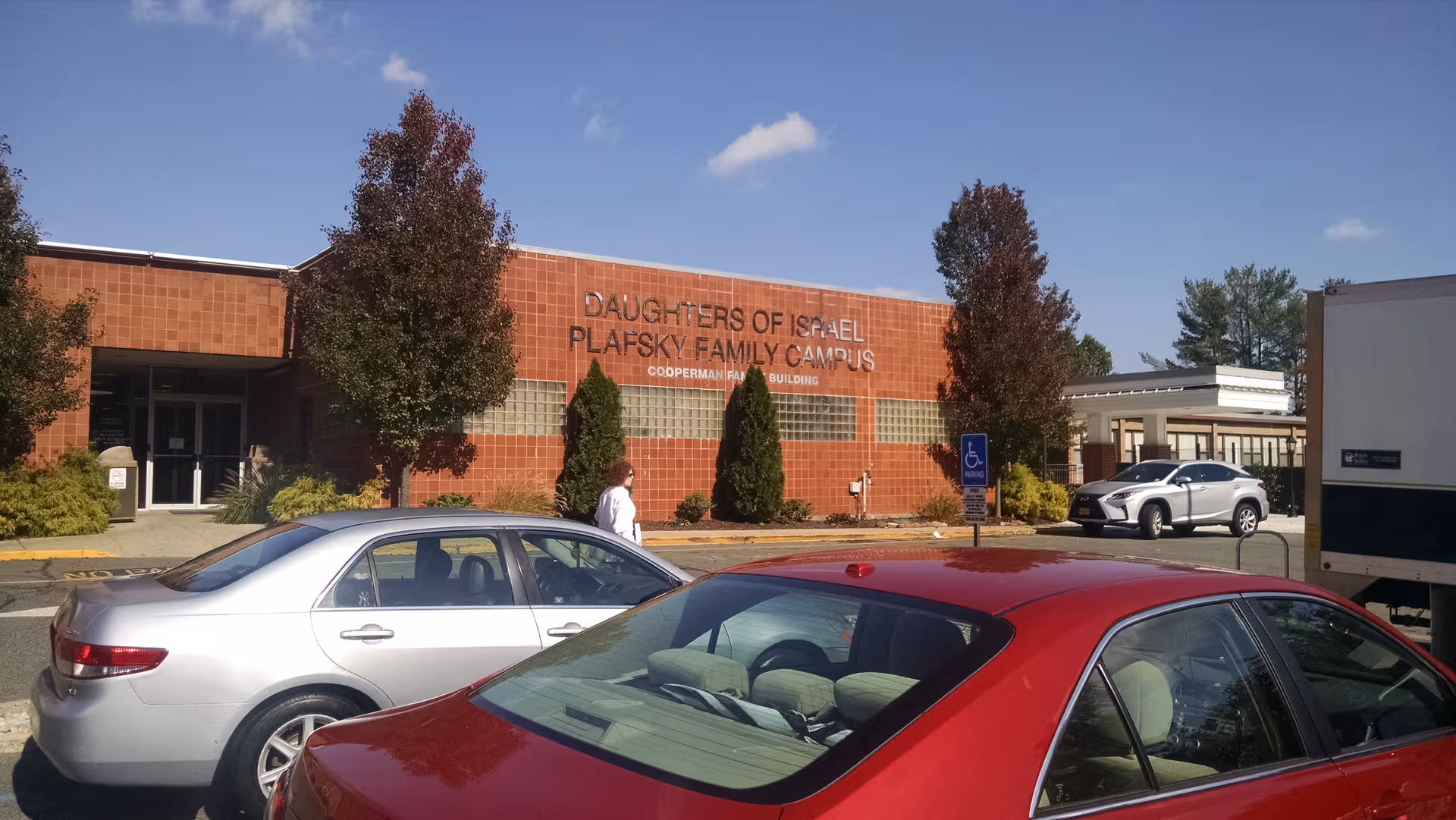 Exterior view of Daughters of Israel Home with red-brick facade and parked cars.