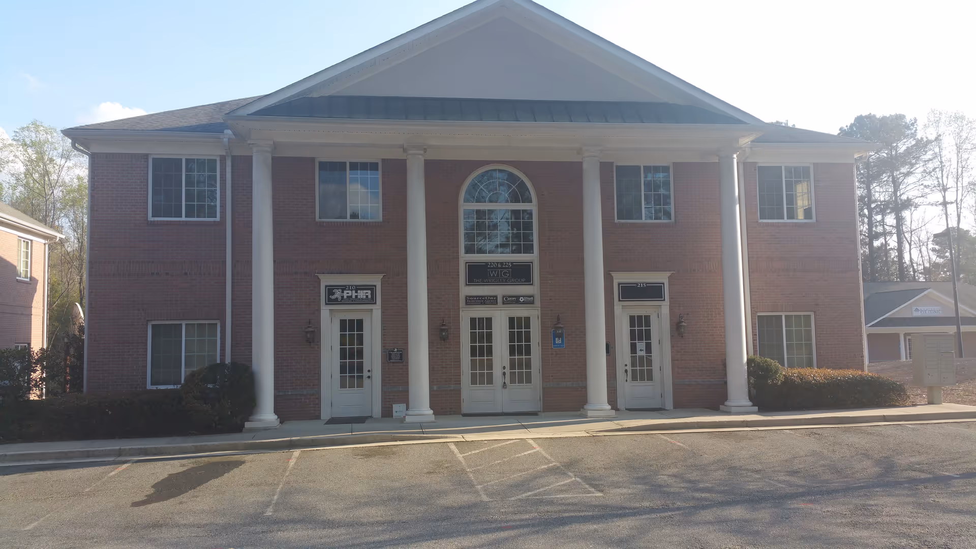 Brick senior living facility with tall white columns, multiple doors, and an arched central window.