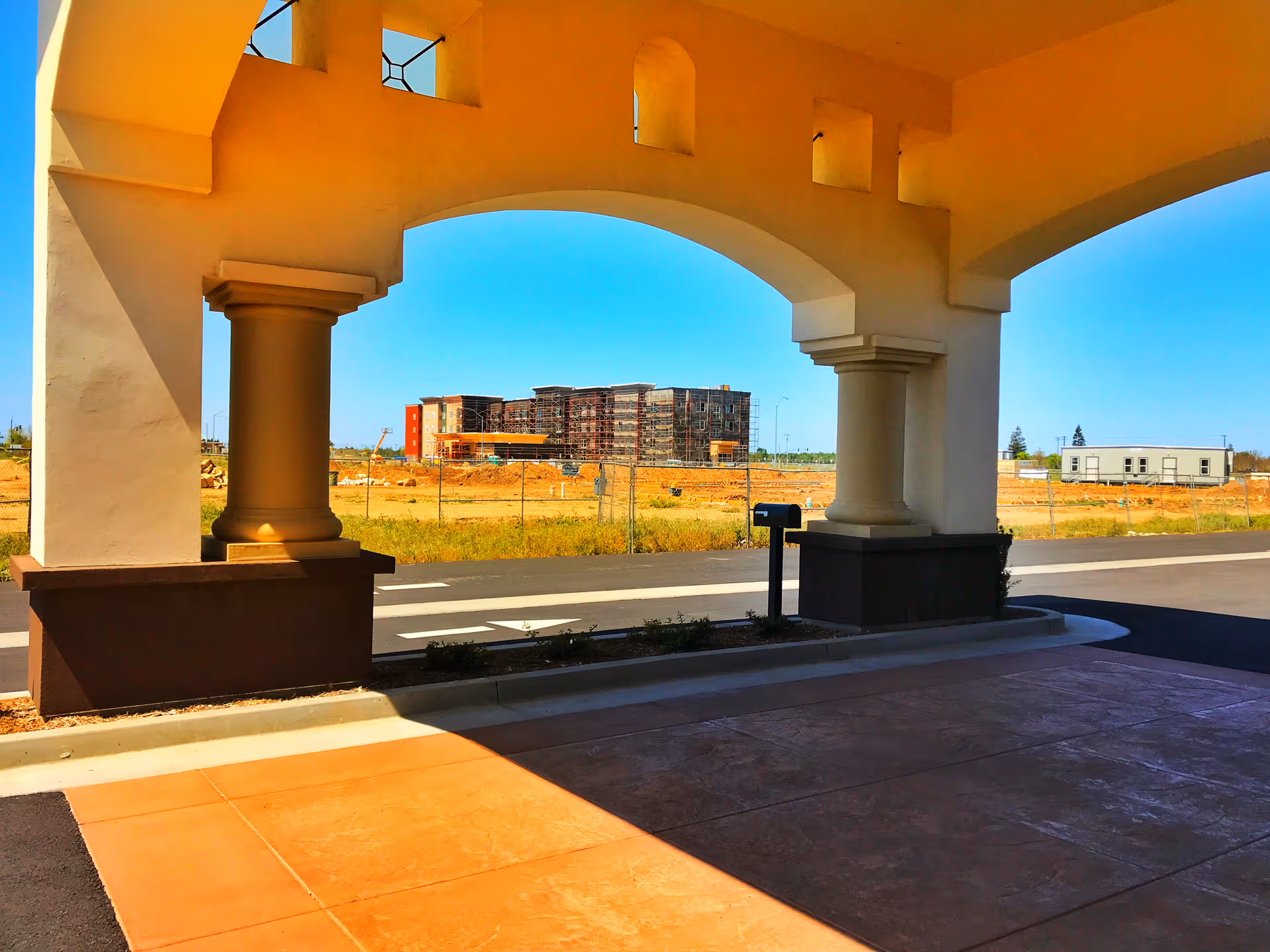 Front of a building under construction with arches and columns.