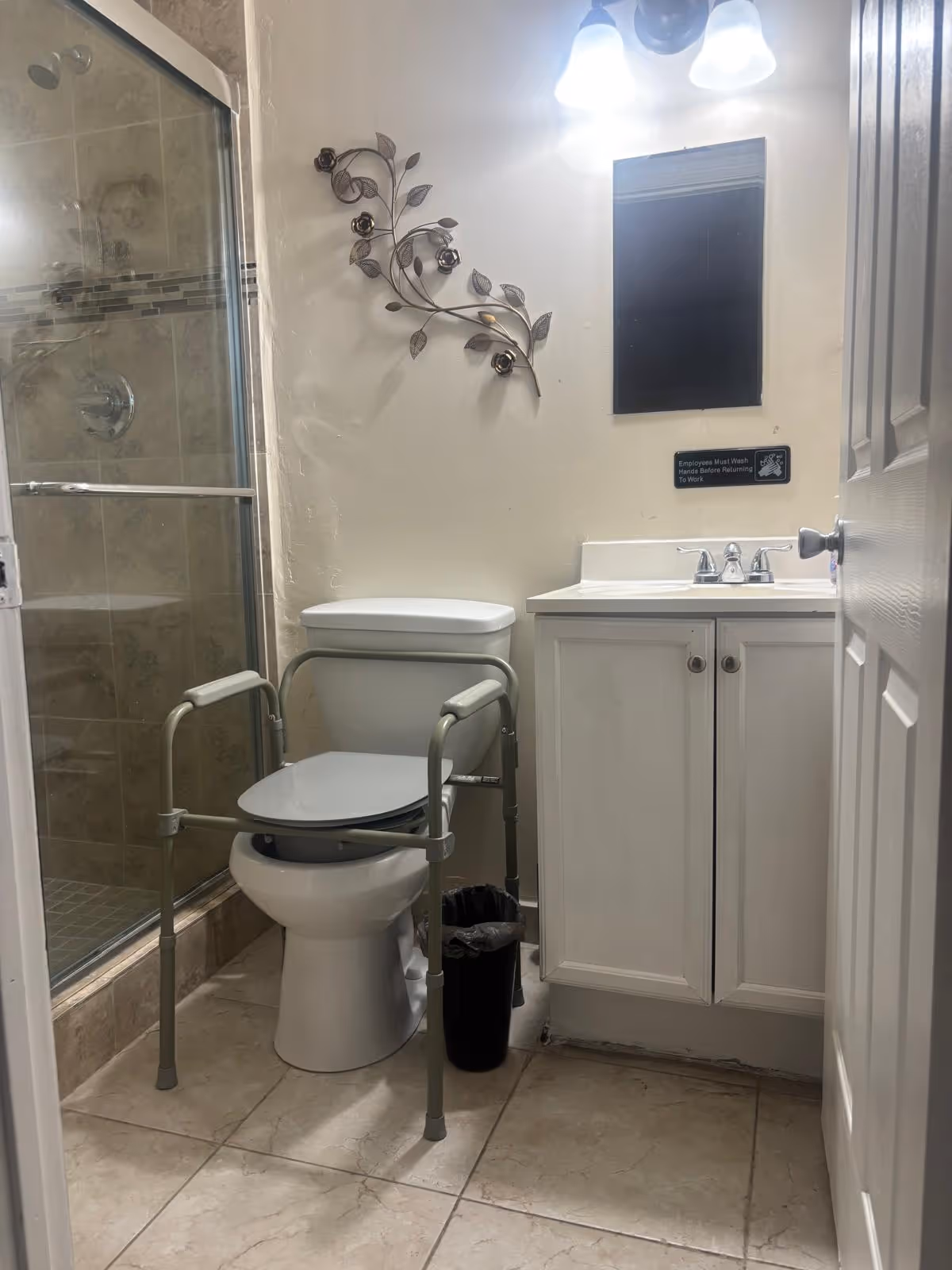 Compact bathroom with shower, toilet, sink vanity, and a mobility aid nearby.