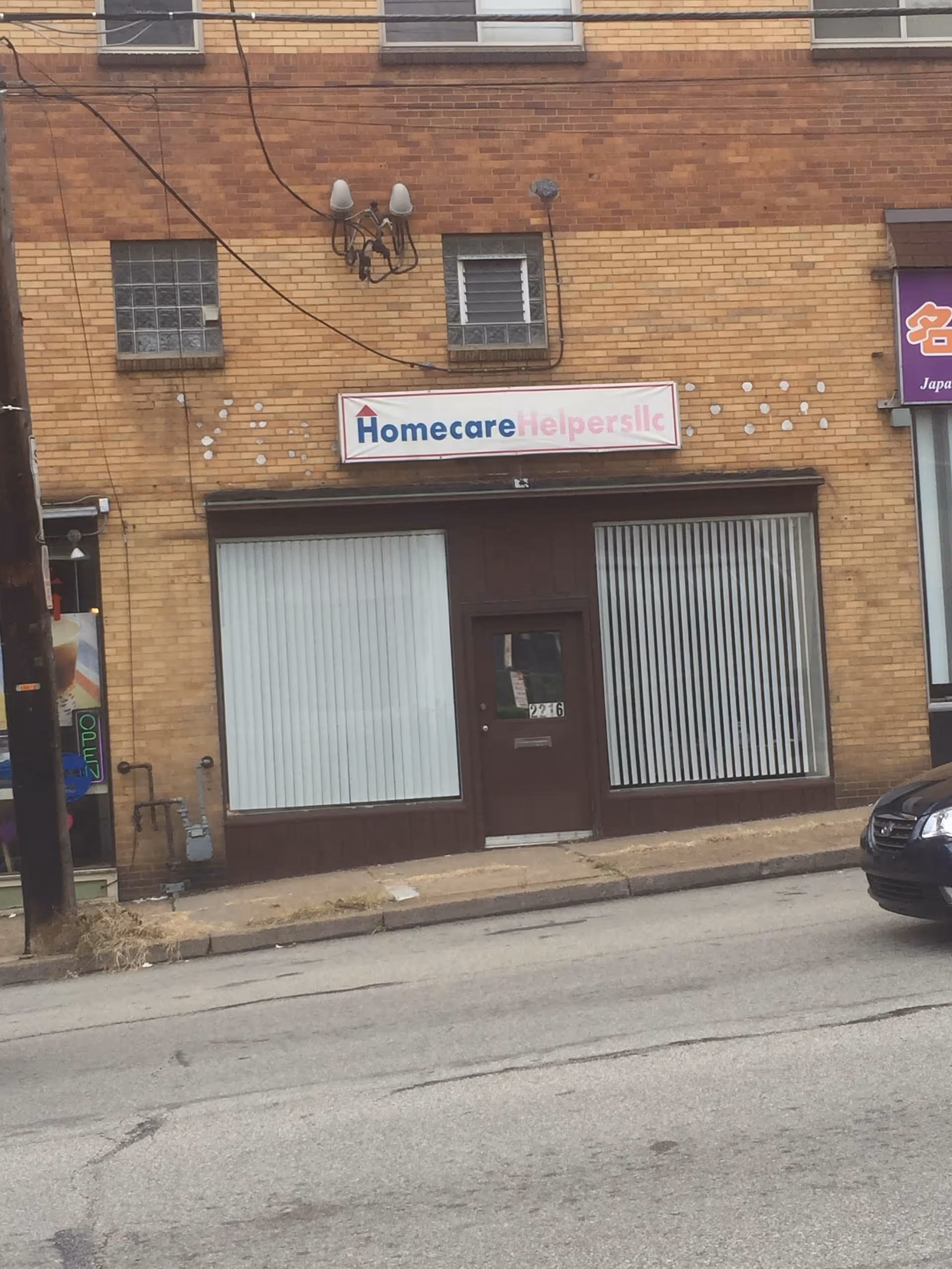 Brick storefront on a city street displaying Homecare Helpers LLC signage.
