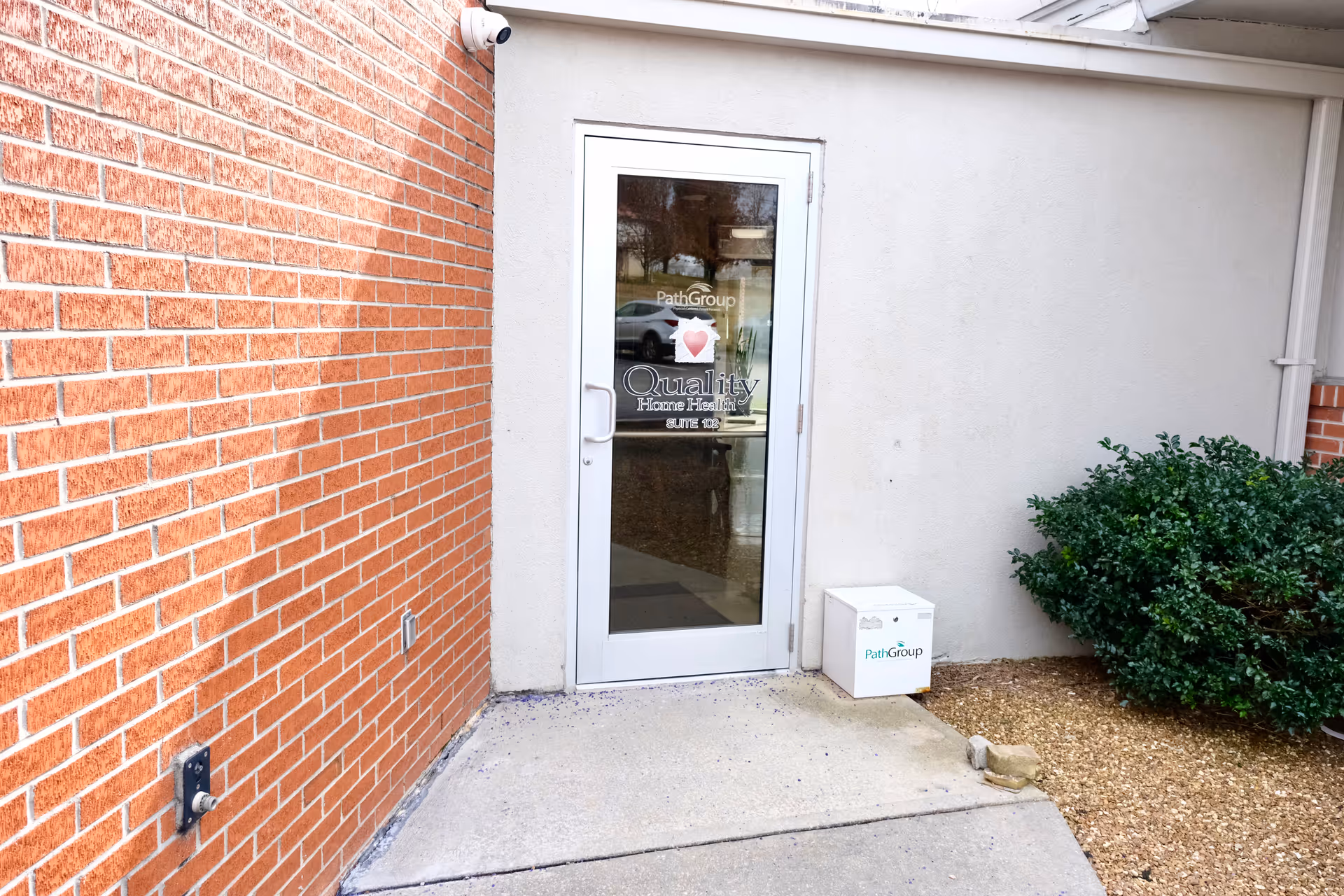 Exterior building entrance with a glass door branded Quality Home Health and PathGroup.
