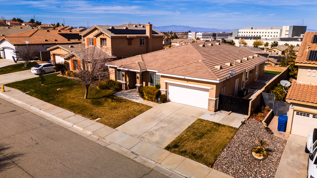 Aerial view of a suburban neighborhood with tan houses, driveways, and manicured lawns.