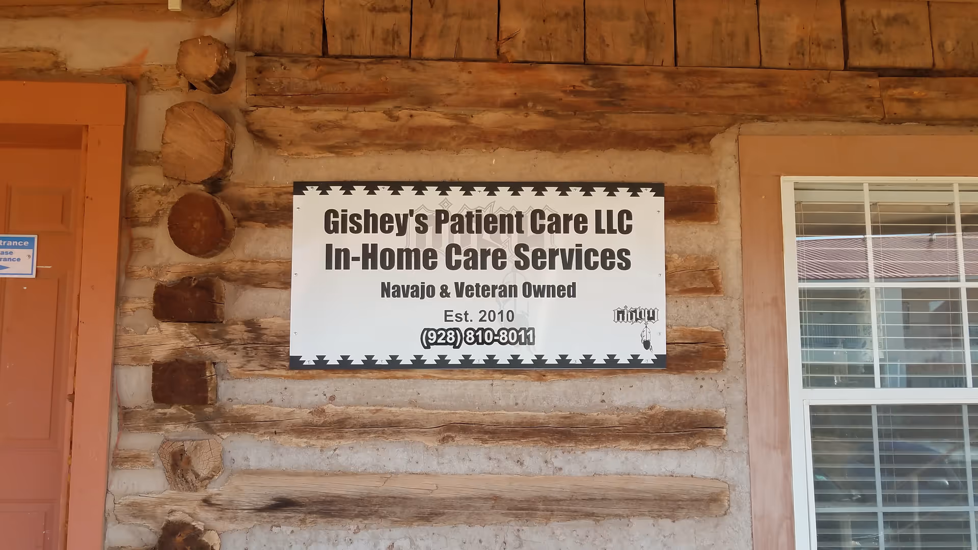 Log cabin exterior featuring a Gishey's Patient Care LLC sign mounted on the wall.