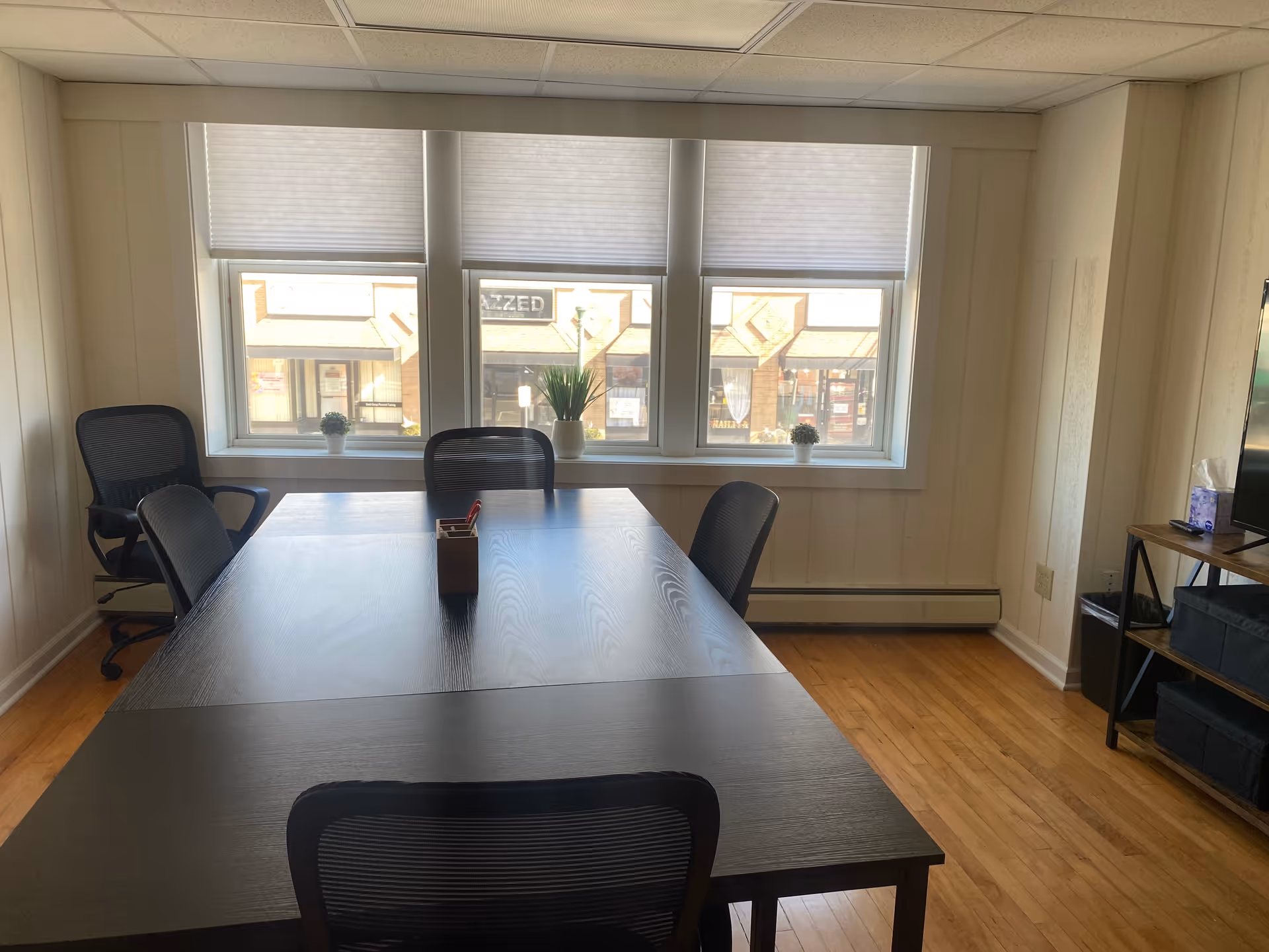 Interior conference room with a long table, chairs, and large windows with blinds.