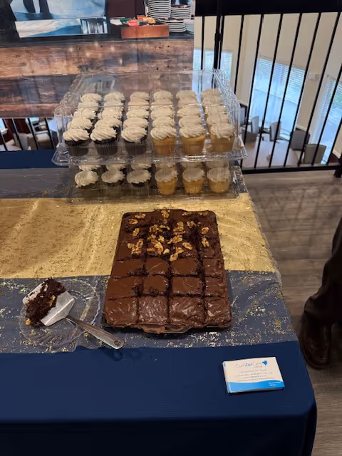 Dessert table featuring cupcakes and chocolate cake in a care facility dining area.