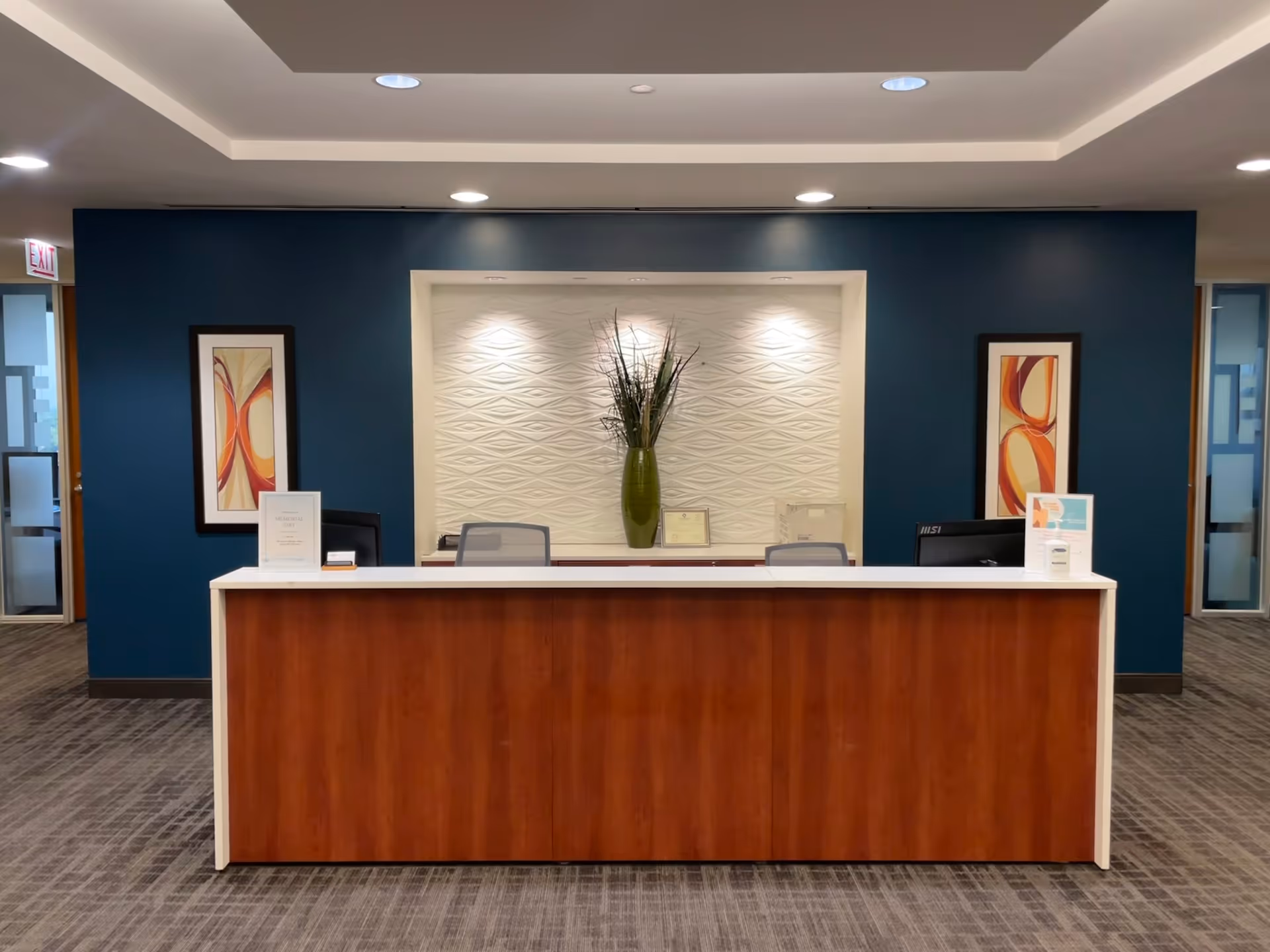 Reception desk in a modern lobby with blue walls and artwork.
