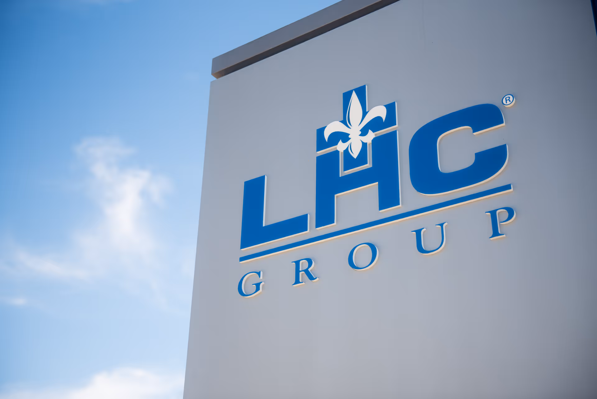 Exterior view of a white wall with a blue LHC Group sign and logo.