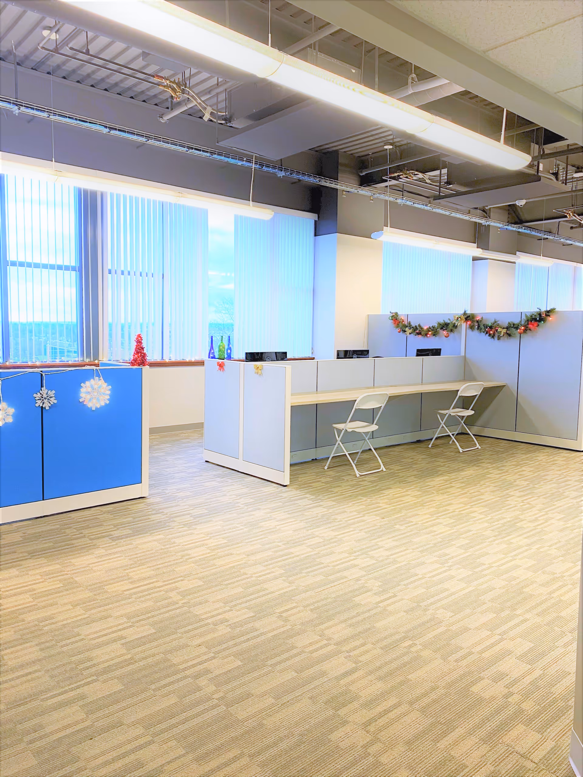 Bright office-like reception area with cubicles, folding chairs, and holiday garland decor.