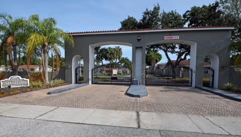 Gated entrance to The Villas of Casa Celeste with arches, palm trees, and brick paving.