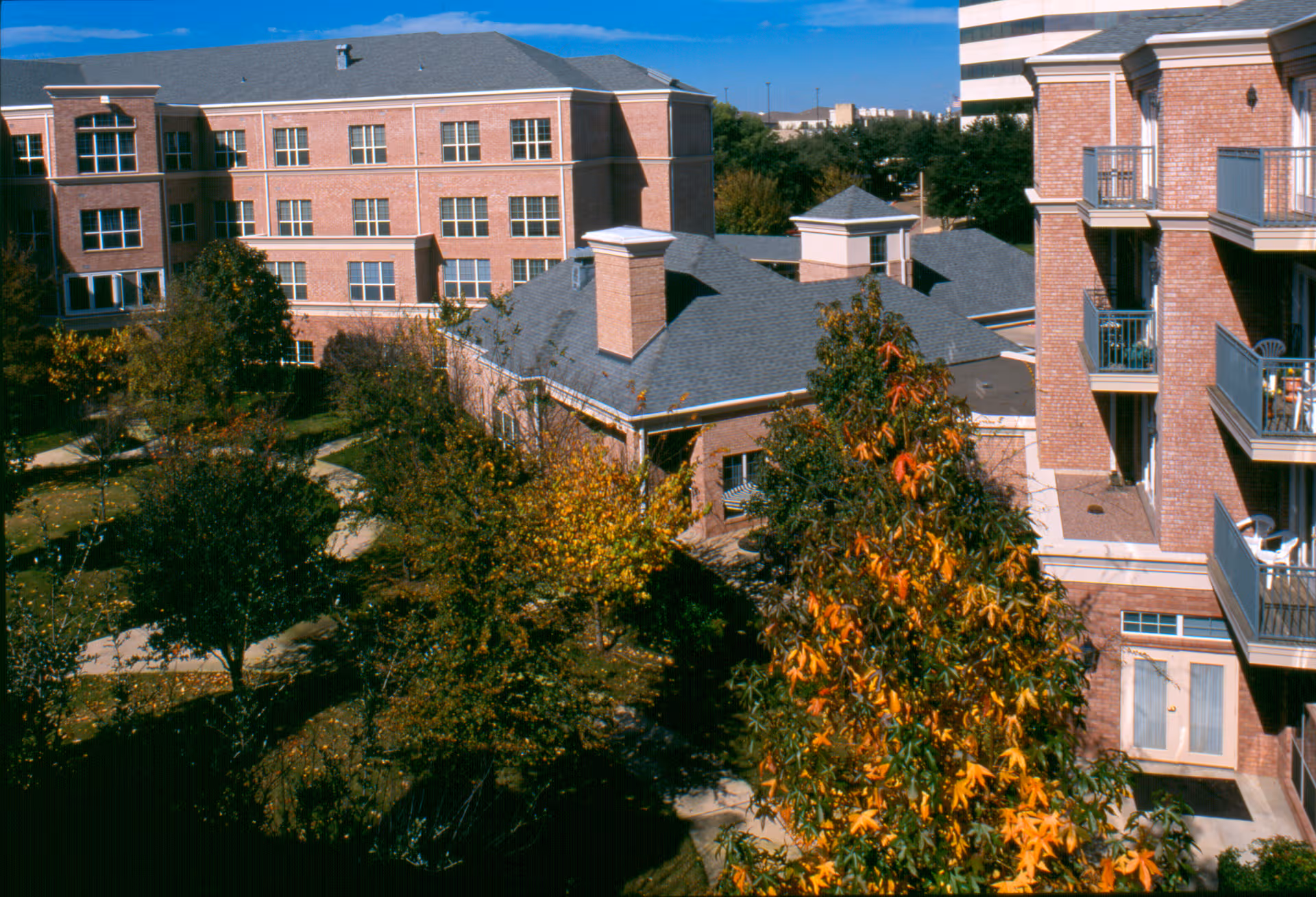 Signature Pointe brick senior living facility exterior with balconies, trees, and blue sky.