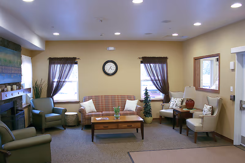Cozy living room with sofa, armchairs, coffee table, fireplace, clock, and curtained windows.
