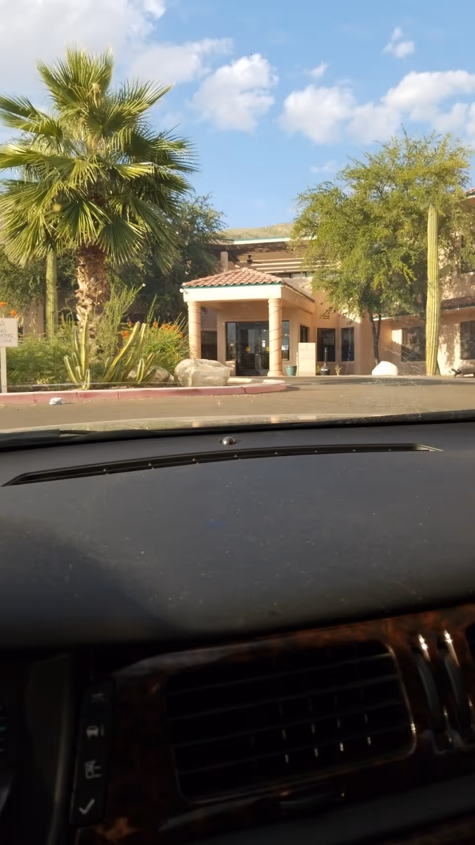 Driver's view of the facility entrance with columns and desert landscaping.