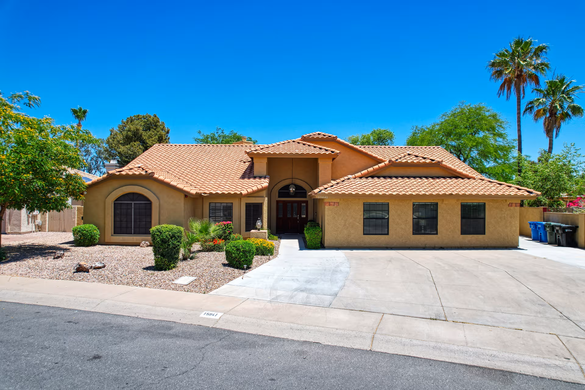 A tan stucco senior living facility with a terracotta tiled roof and desert landscaping.