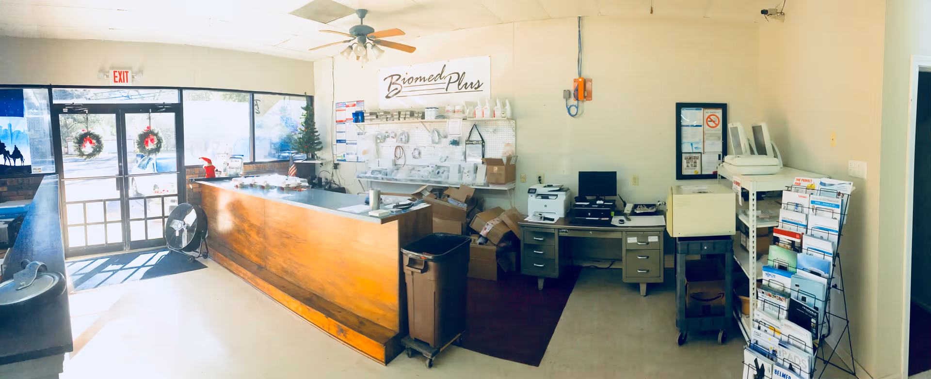 Interior reception area with a wooden counter, medical equipment, and Biomed Plus sign.