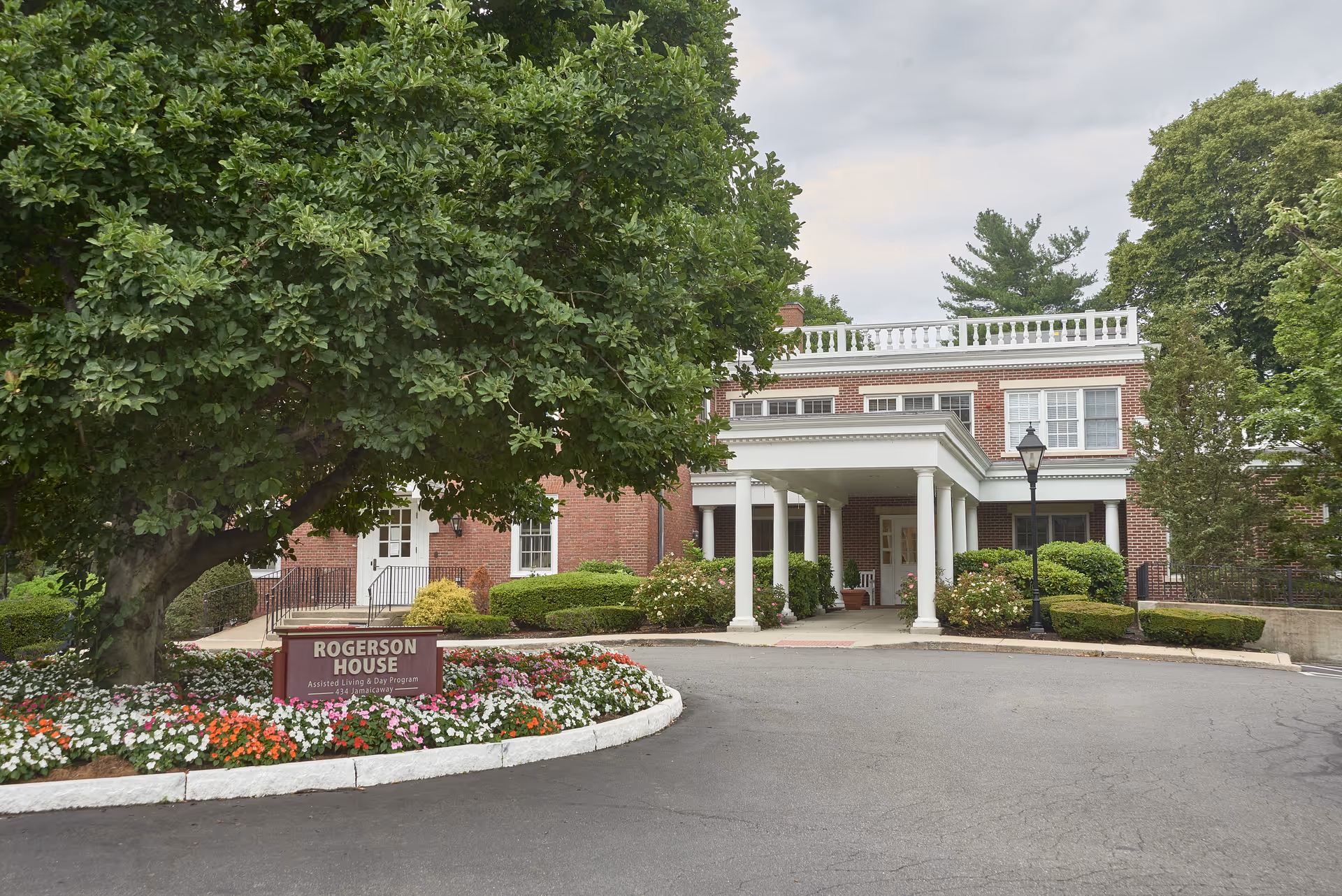 Front view of Rogerson House memory care facility with brick facade, portico, and landscaped grounds