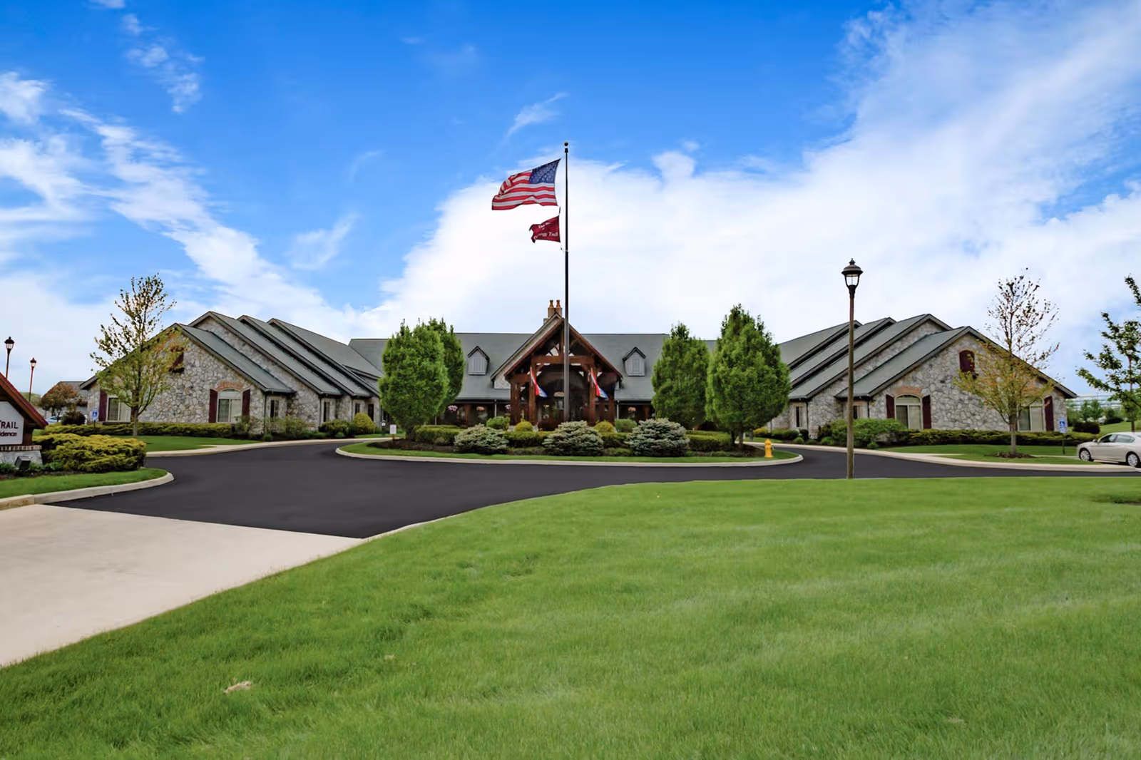 Front view of The Inn at Walnut Trail with circular drive, flag, and landscaped entrance.