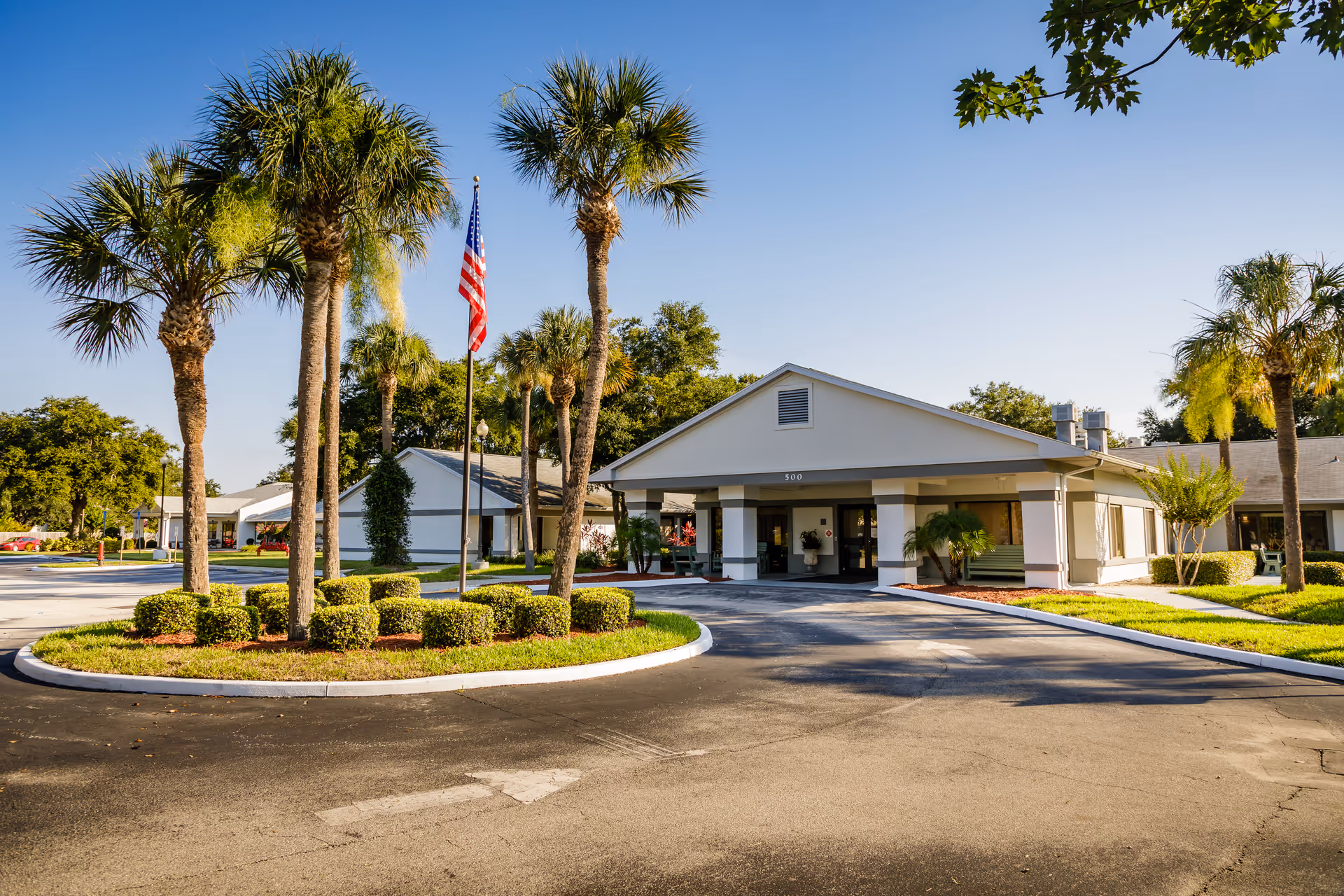 Sunlit entrance to Solaris Healthcare Merritt Island with circular driveway and palm trees.