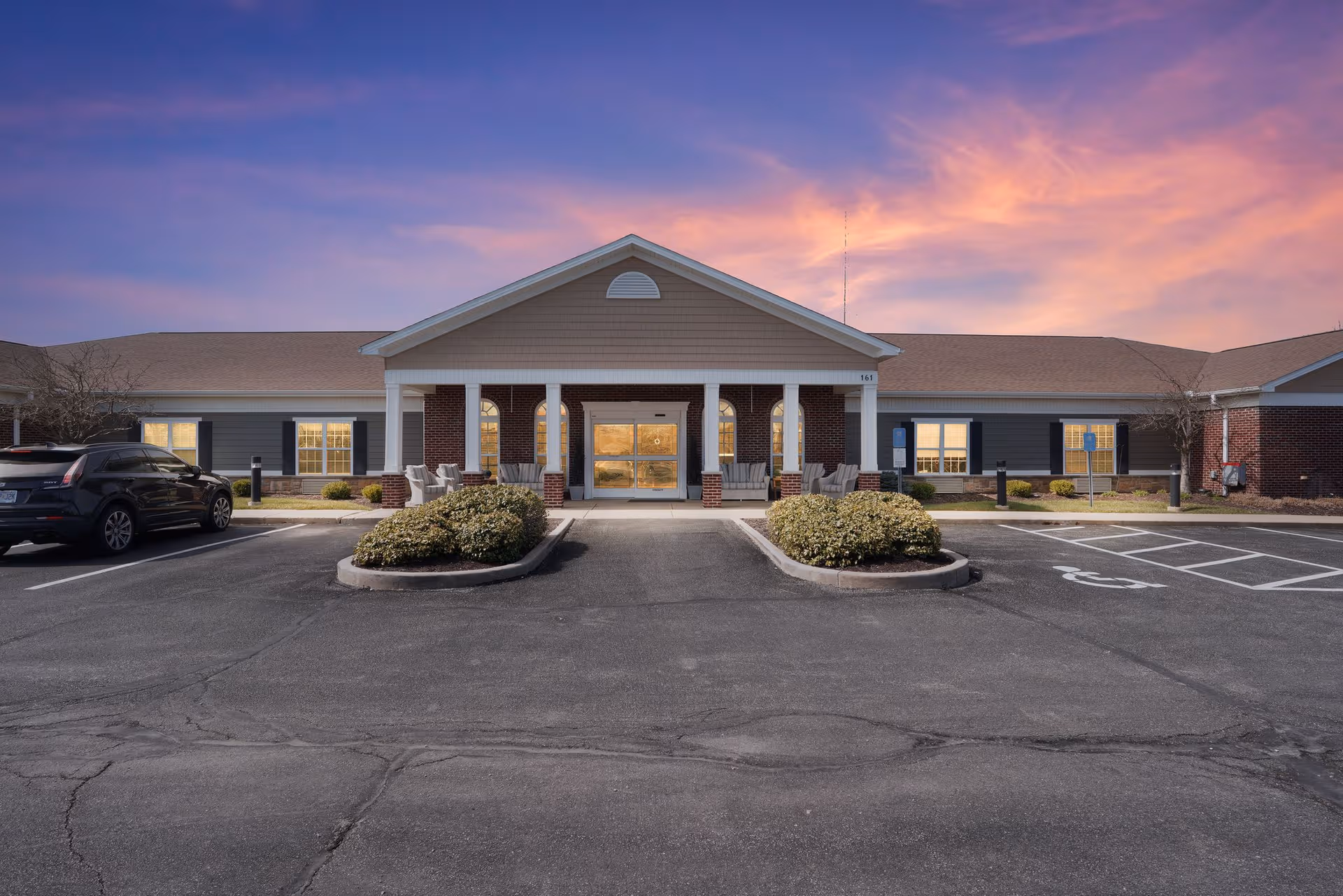 Front view of Sugar Creek Senior Living facility with parked cars and welcoming entrance.