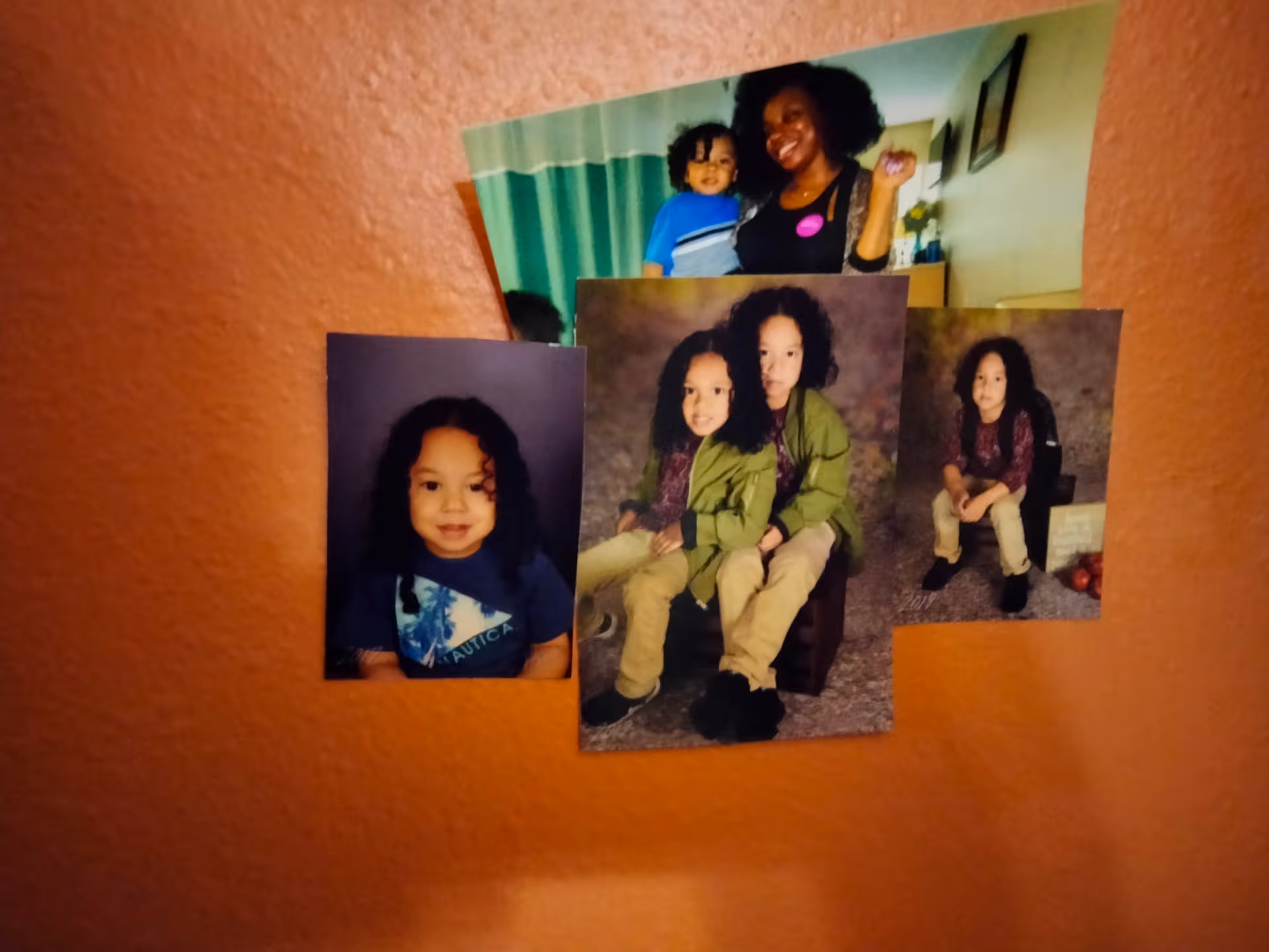 Collage of family photos displayed on an orange interior wall.