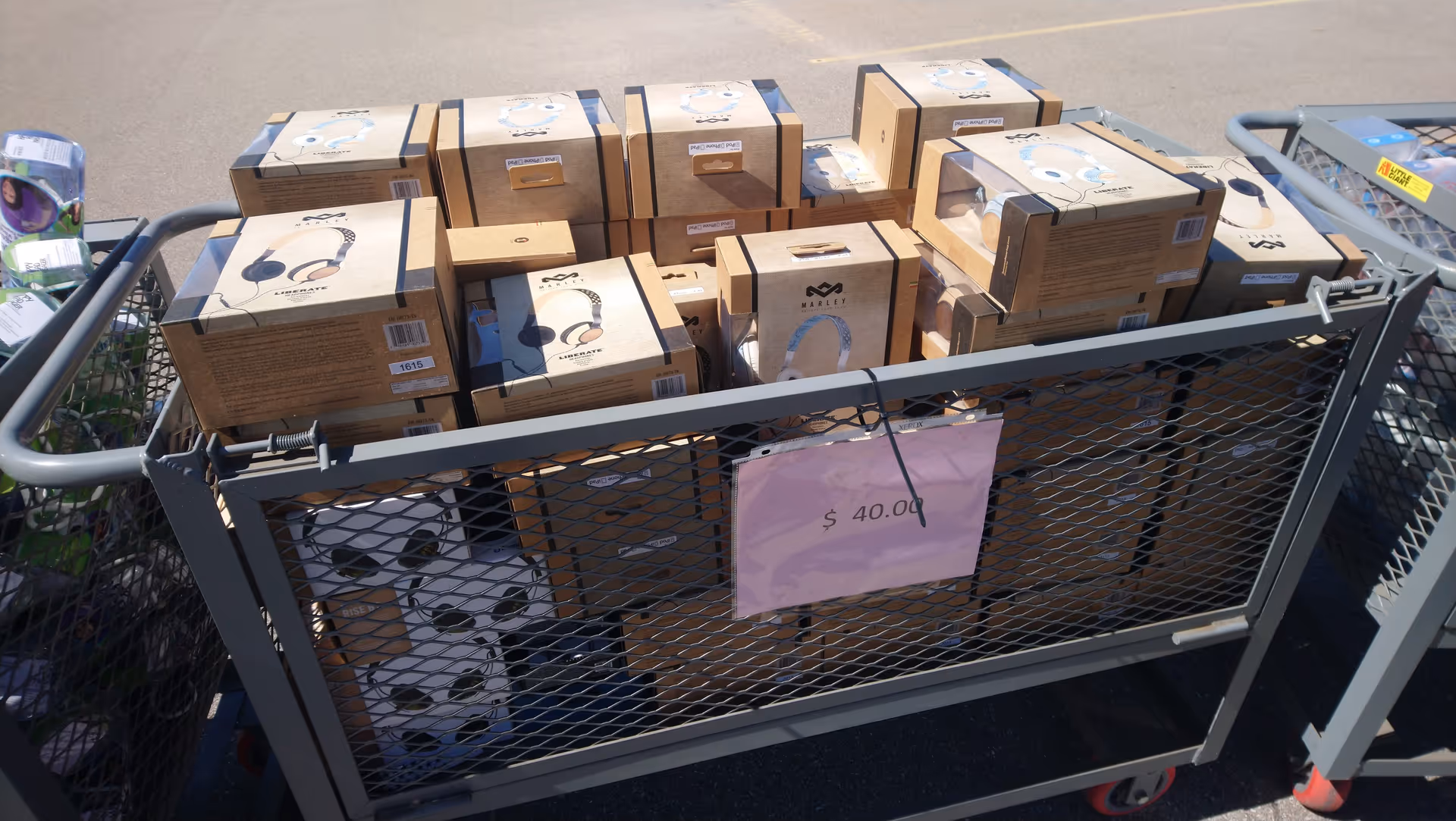 Cart loaded with HoMedics boxes outdoors, pink price sign shows $40.00.