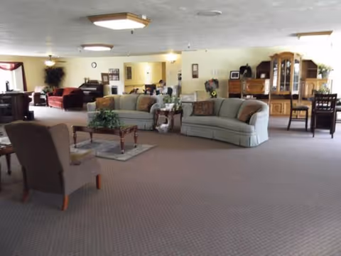 Spacious senior living lounge with multiple sofas, chairs, and coffee tables.