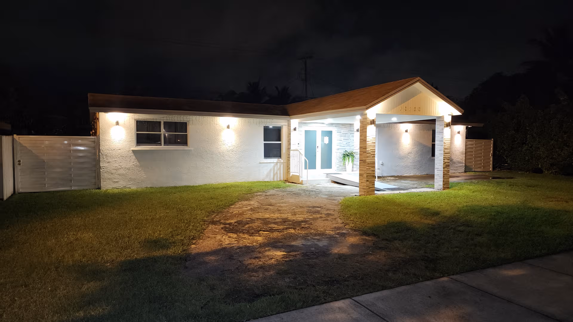 Nighttime exterior of Ave Fenix ALF LLC, a single-story white building with lit entry.