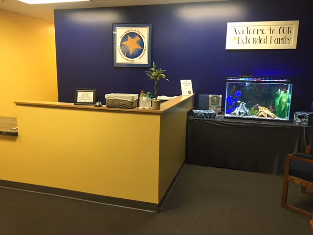 Reception desk in a yellow and blue lobby with an aquarium and welcome sign.