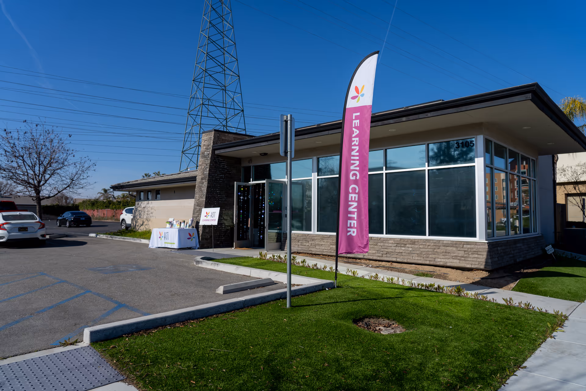 Exterior view of an Autism Spectrum Therapies AST building with glass windows and a purple flag.